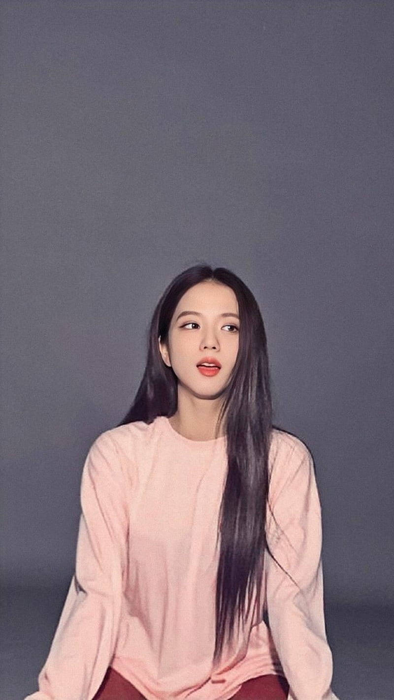 Jisoo Cute 桌布 壁紙 — 一位長黑髮的年輕女性穿著柔軟的粉紅色毛衣，背景是柔和的灰色攝影棚。