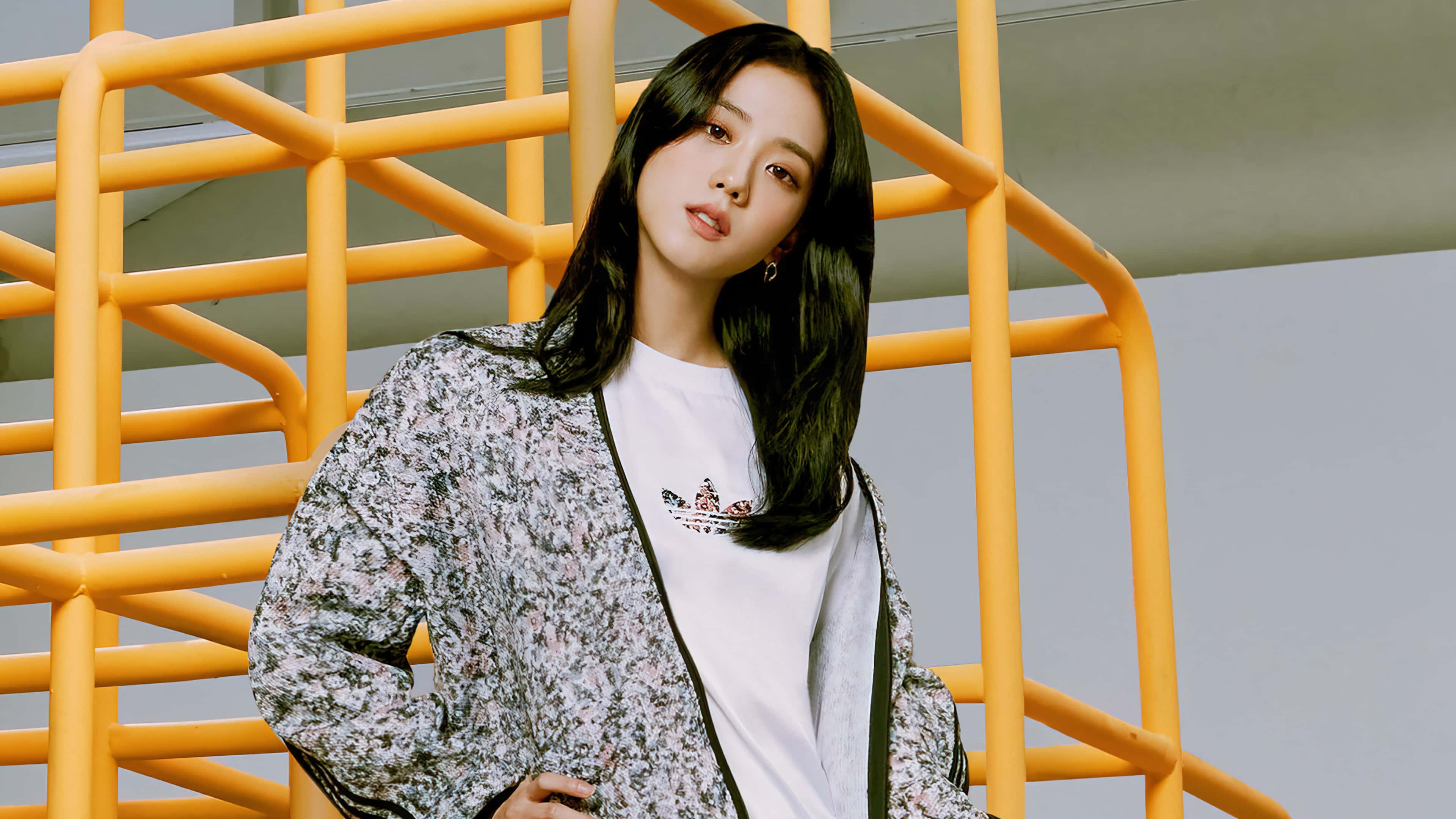 BLACKPINK 桌布 壁紙 — 一位長黑髮的年輕女性穿著花卉圖案外套，在搶眼的黃色金屬樓梯結構前自信地擺姿勢。