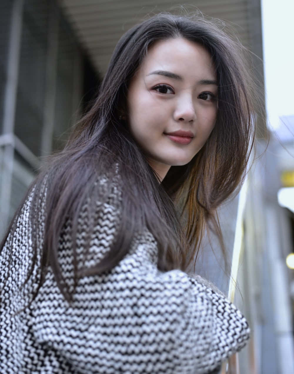 美女 桌布 壁紙 — 一位長黑髮的年輕女性穿著黑白千鳥格毛衣，在戶外面對鏡頭。