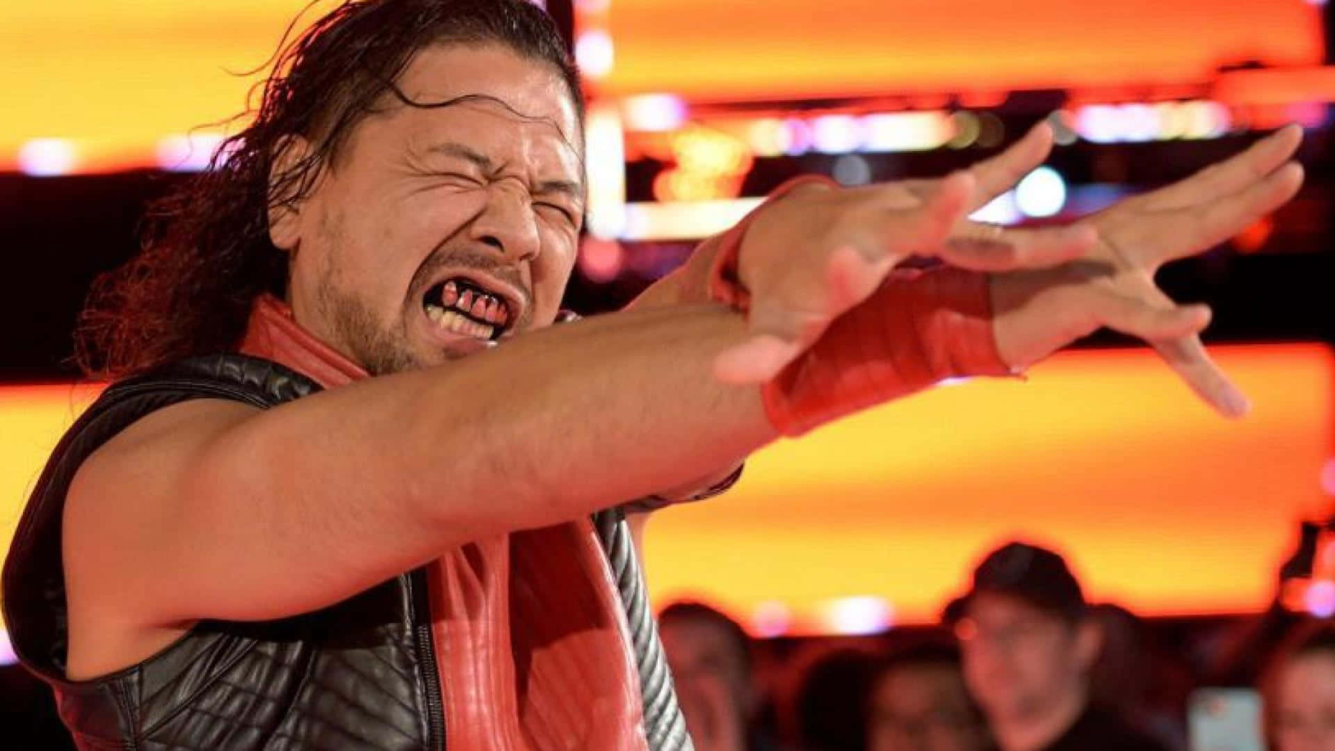WWE 桌布 壁紙 — 一位長黑髮的摔角手在明亮的橙色燈光下，在摔角場中伸出雙臂，激烈地尖叫。