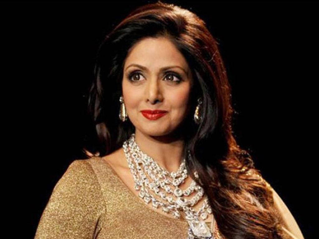 Sridevi 桌布 壁紙 — 一位長黑髮的迷人女性，身穿金色服裝，佩戴閃耀鑽石首飾，背景為黑色。