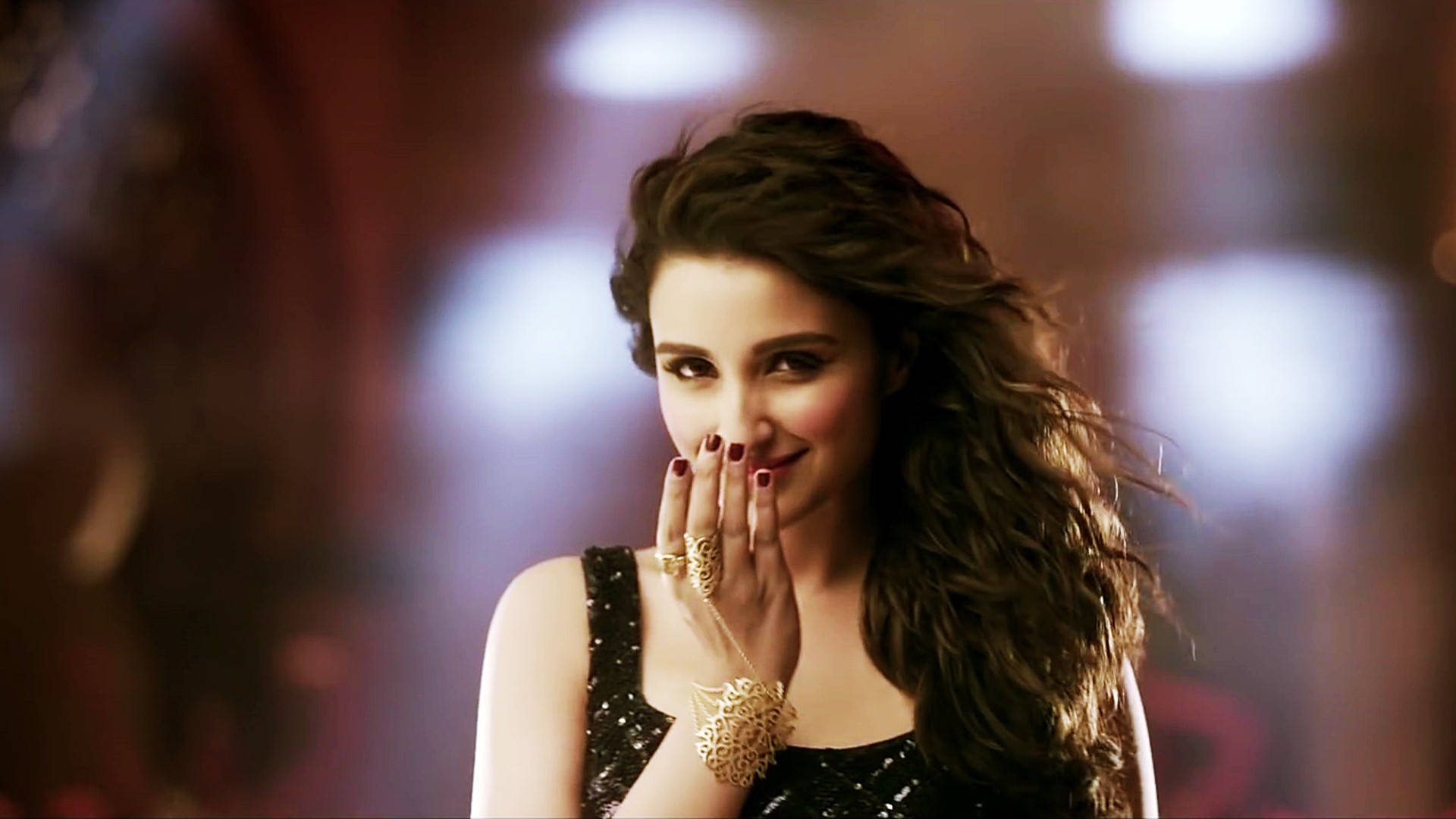 Parineeti 桌布 壁紙 — 一位長黑髮紅指甲的女性微笑著，用戴著金飾的手遮住嘴巴。
