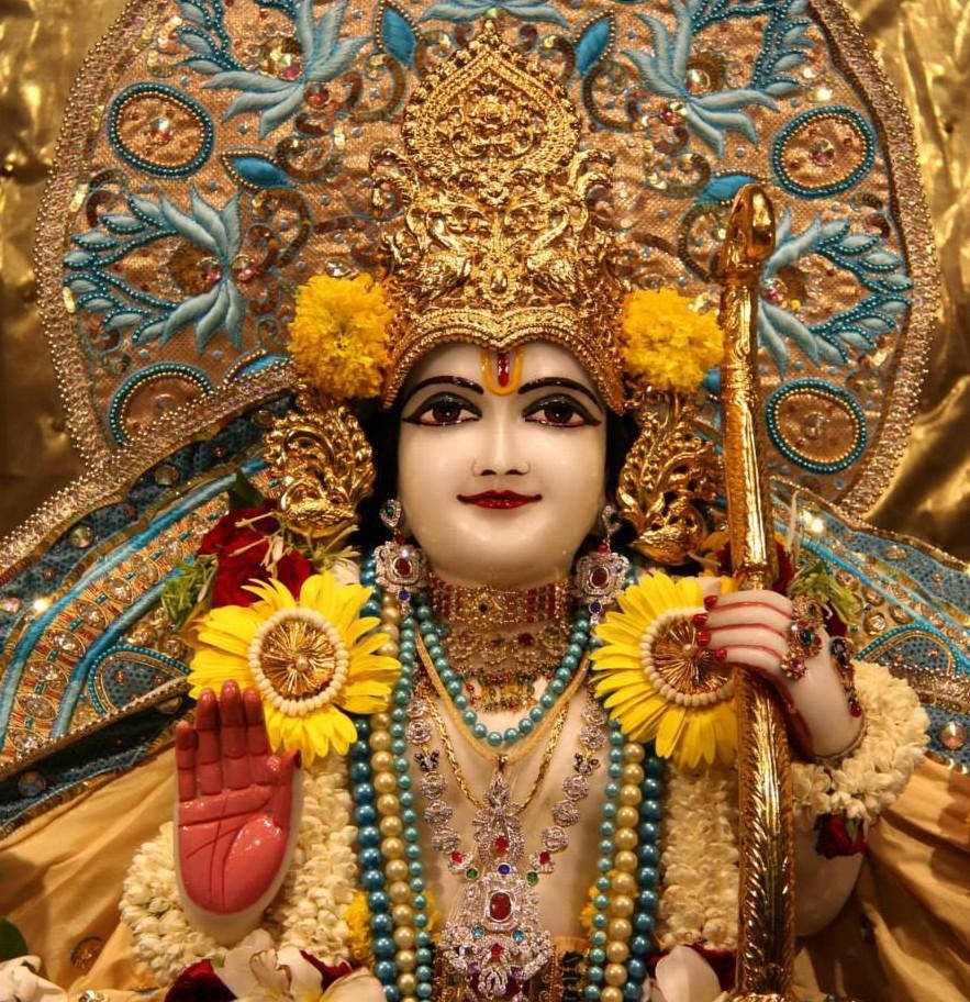 jai shri ram 桌布 壁紙 — 一位閃耀的印度教神祇，佩戴金色珠寶和藍色花卉圖案，在閃爍的金色背景下手持權杖和向日葵。