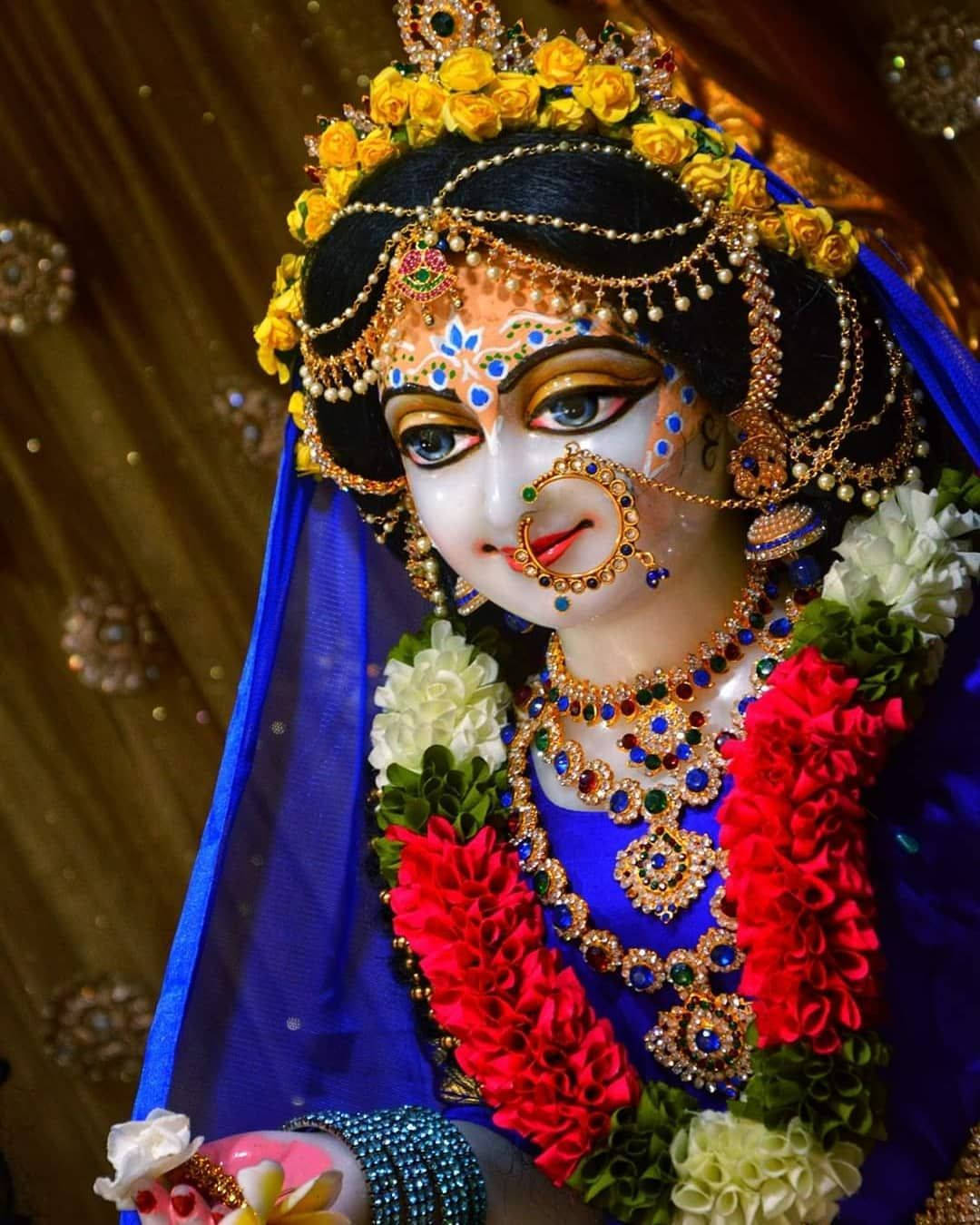 radha krishna HD 桌布 壁紙 — 一位閃耀的神祇，飾以金色珠寶、黃玫瑰和紅白花環，襯以華麗的金色背景。
