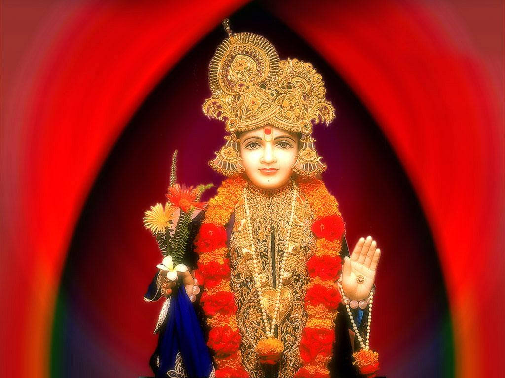 Swaminarayan 桌布 壁紙 — 一位閃耀的金色神祇，裝飾著紅色和橙色的花環，站在黑暗背景中發光的紅色拱門內。