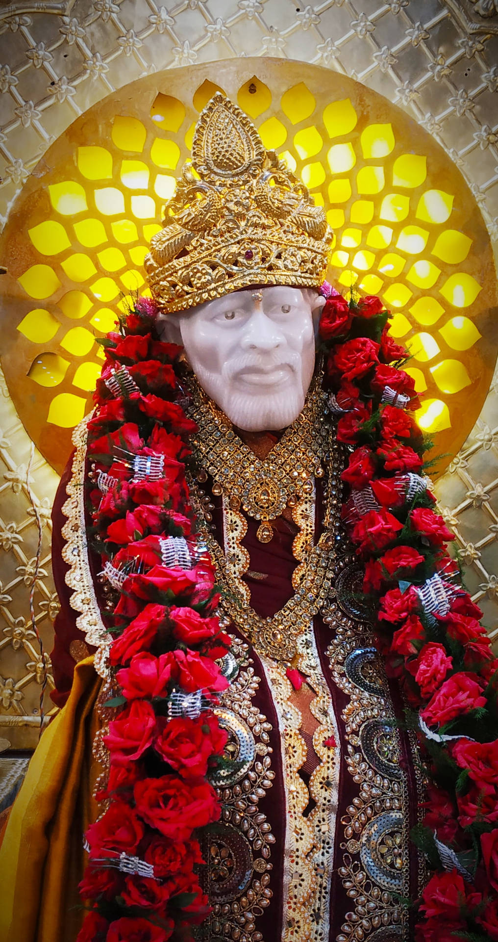 金色神像披著紅玫瑰和裝飾性珠寶，以陽光為背景。 — Sai Baba 高畫質壁紙 壁紙
