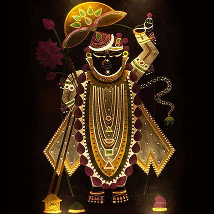 Shrinathji 桌布 壁紙 — 一位閃耀的金色神祇，飾有精緻珠寶和蓮花冠，立於深色背景前。