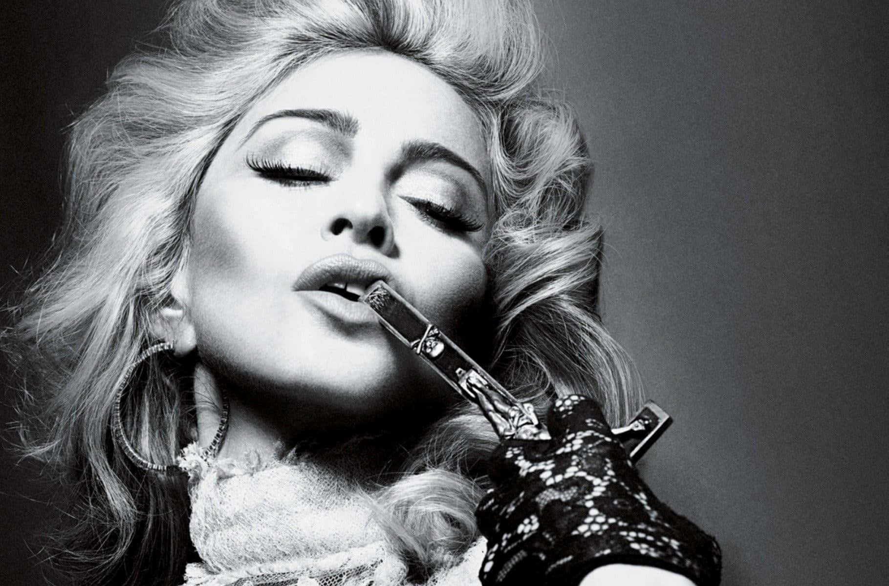 Madonna 桌布 壁紙 — 一位閉著眼睛、擁有豐盈金髮的迷人女性，在戲劇性的黑白肖像中將匕首貼在唇邊。