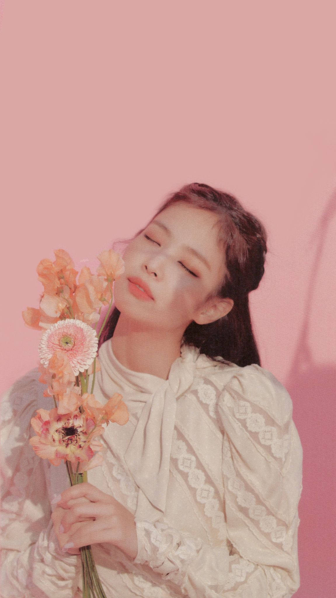BLACKPINK 桌布 壁紙 — 一位閉著眼睛的女性在柔和的粉紅色背景前輕輕捧著一束蜜桃色和白色的花。
