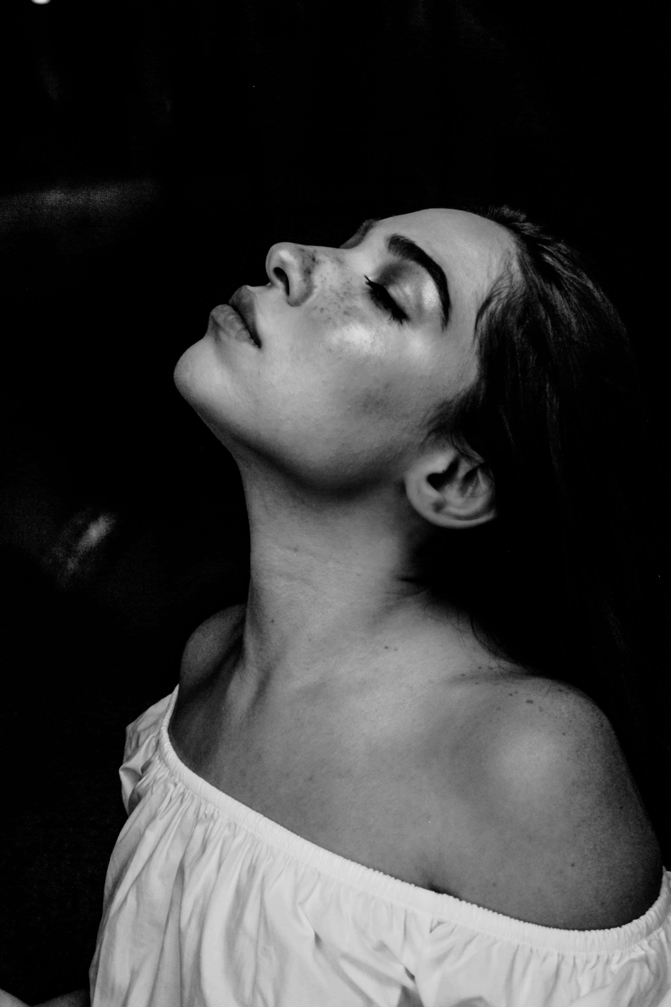 Monochrome 桌布 壁紙 — 一位閉著眼睛的女性在純黑背景下，頭向後傾，呈現寧靜的休憩姿態。