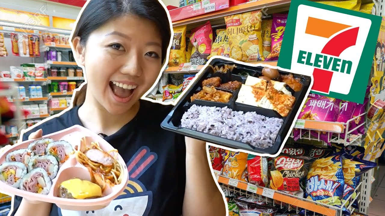 7-ELEVEN 桌布 壁紙 — 一位開心的女士在光線明亮的7-Eleven店鋪通道中，手持兩個色彩繽紛的便當盒，笑容燦爛。