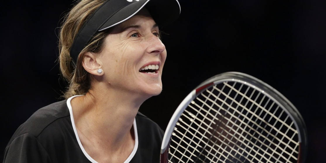 Monica Seles 桌布 壁紙 — 一位開心的女網球運動員在深色背景下拿著球拍，露出燦爛的笑容。