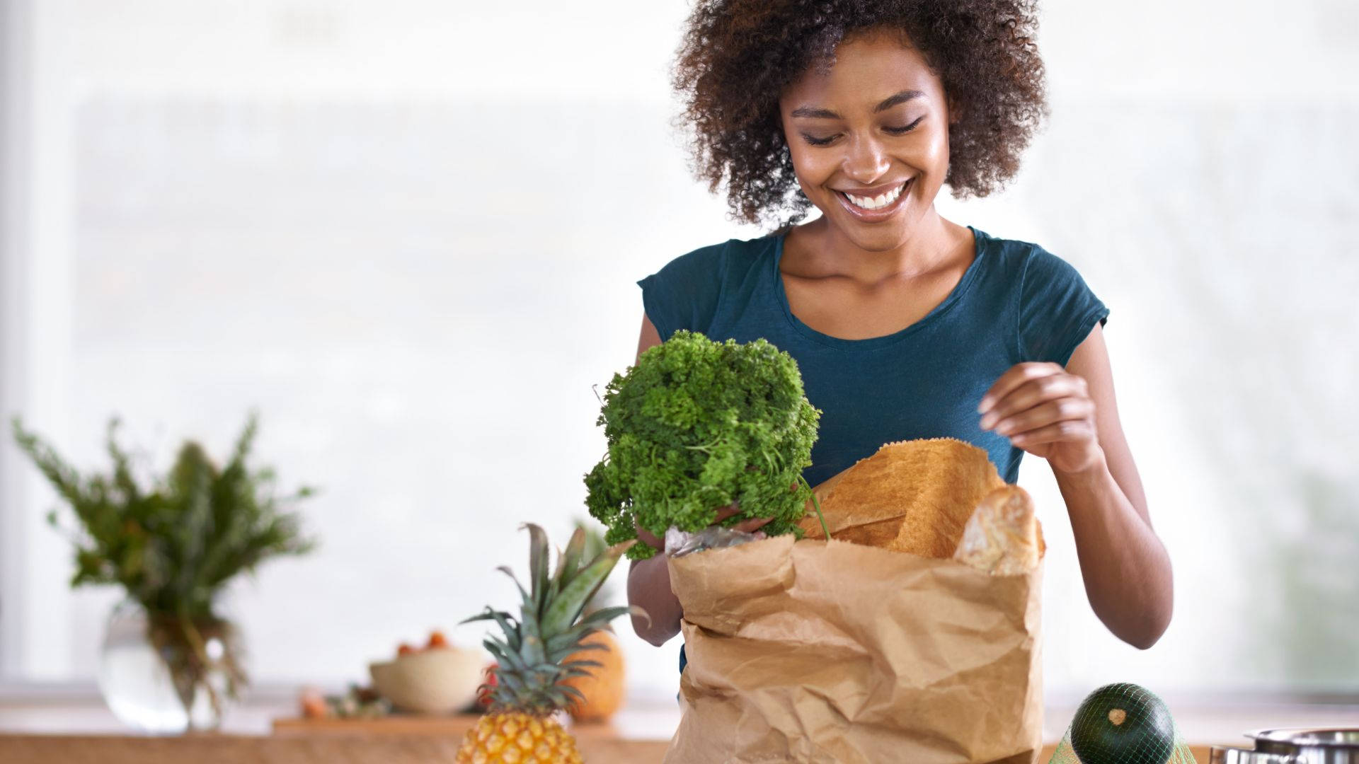 Vegetables 桌布 壁紙 — 一位開心的捲髮女士微笑著從棕色紙購物袋中拿出新鮮的綠色羽衣甘藍。