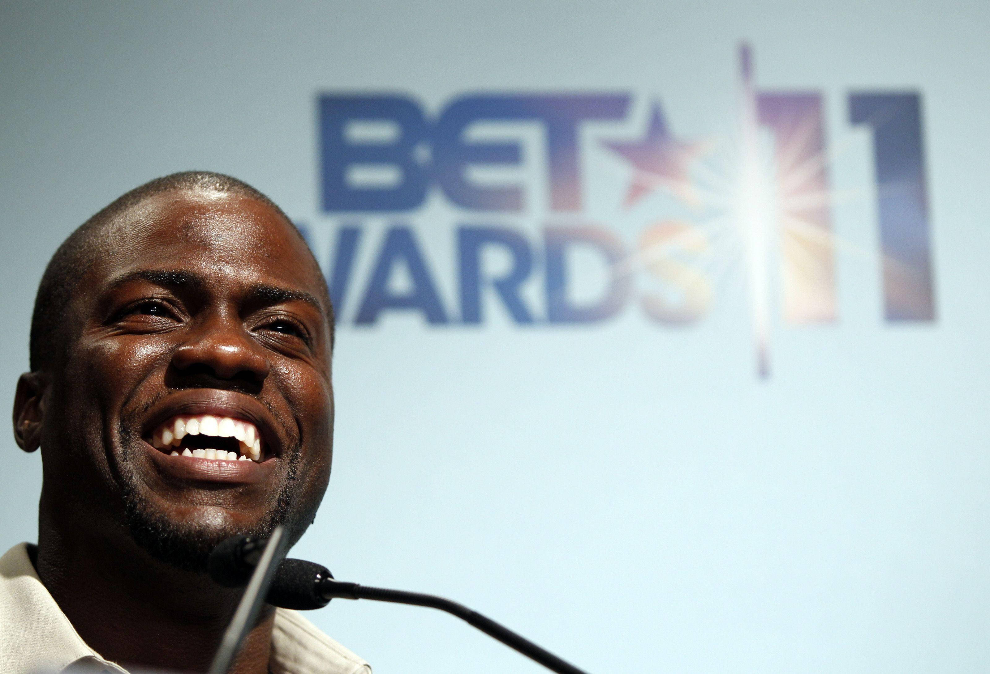Hart 桌布 壁紙 — 一位開心的男士在BET Awards記者會上開懷大笑，身後有明亮的聚光燈。