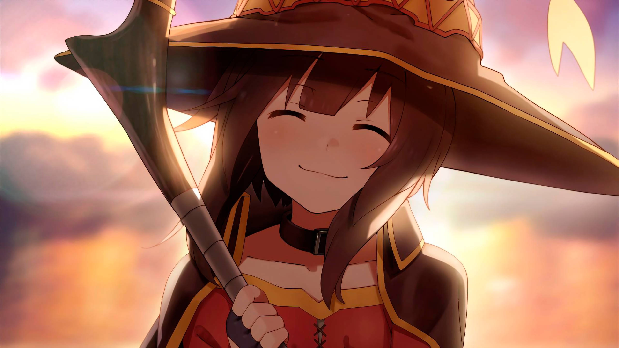 Megumin 桌布 壁紙 — 一位開朗的動漫女巫戴著寬邊帽，在燦爛的日落天空下微笑著拿著法杖。
