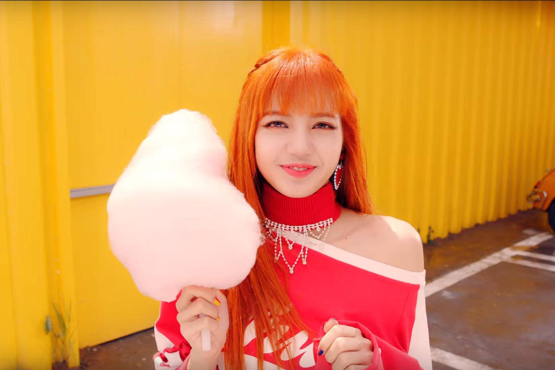 橙色頭髮的女士在黃色牆前拿著粉紅色棉花糖 — BLACKPINK Lisa GIF 壁紙