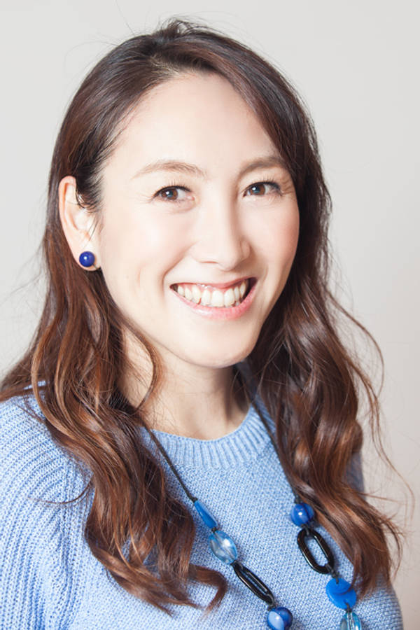 Celebrity 桌布 壁紙 — 一位開朗的女性，波浪形棕色頭髮，穿著藍色針織毛衣和藍色珠子項鍊，溫暖地微笑。