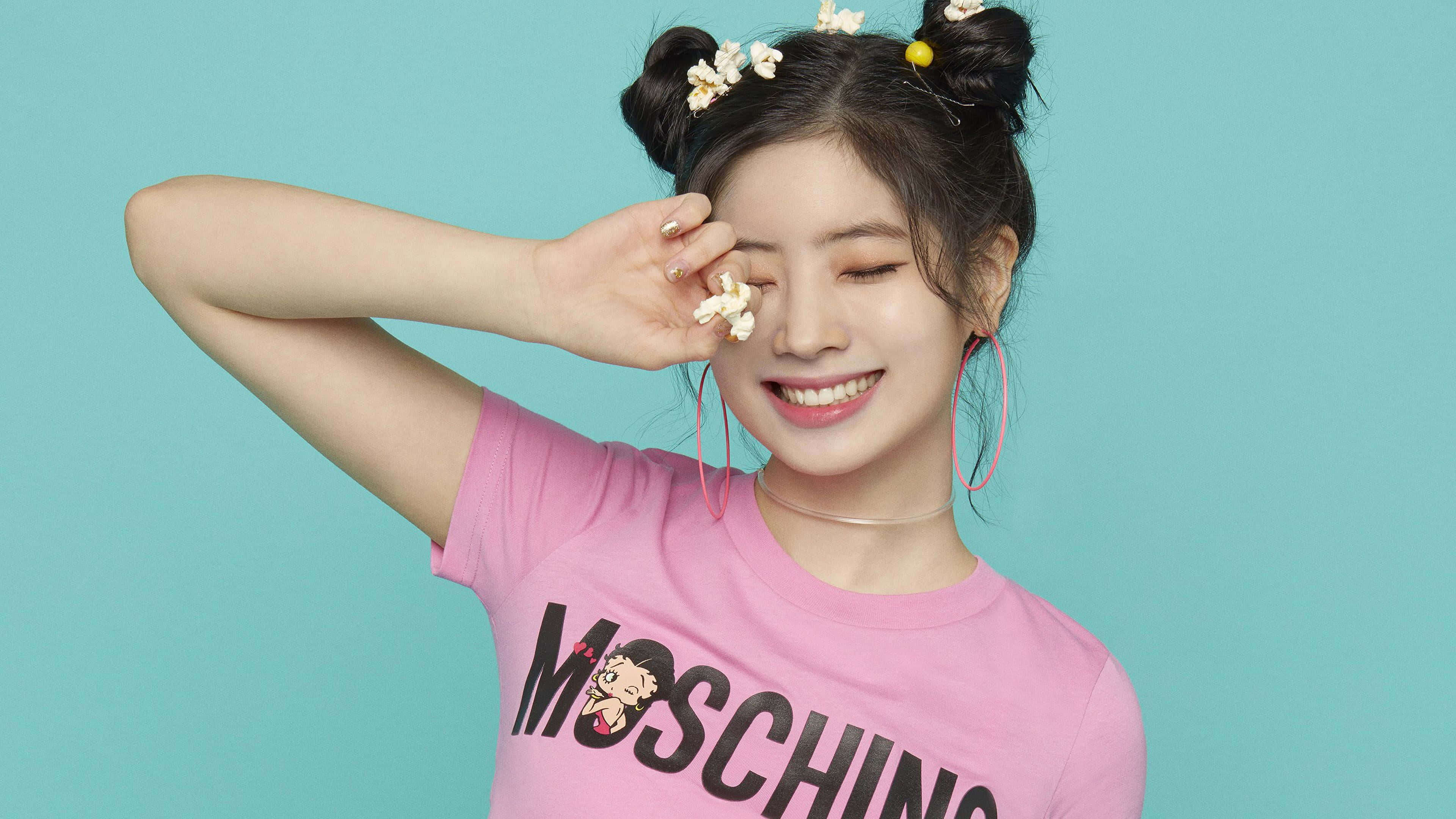 twice 桌布 壁紙 — 一位開朗的年輕女性，雙丸子頭飾有花朵，微笑著用爆米花頑皮地遮住眼睛。