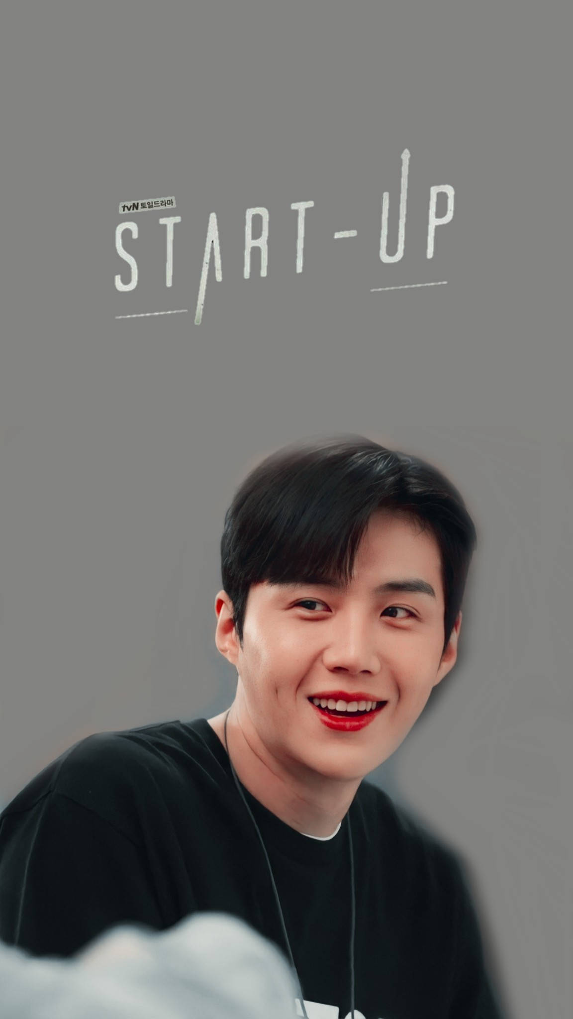 Kim Seon Ho 桌布 壁紙 — 一位開朗的年輕男子塗著鮮紅色唇膏，在帶有「START-UP」文字的純灰色背景上溫暖地微笑。