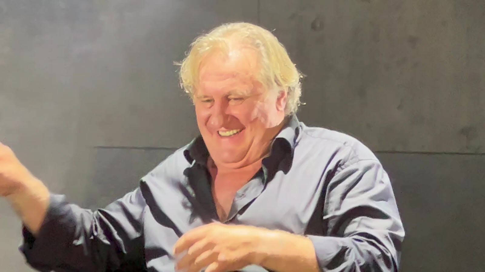 Smile 桌布 壁紙 — 一位開朗的白髮長者，金髮，對著素淨的灰色牆壁，一邊生動地做手勢，一邊開懷大笑。
