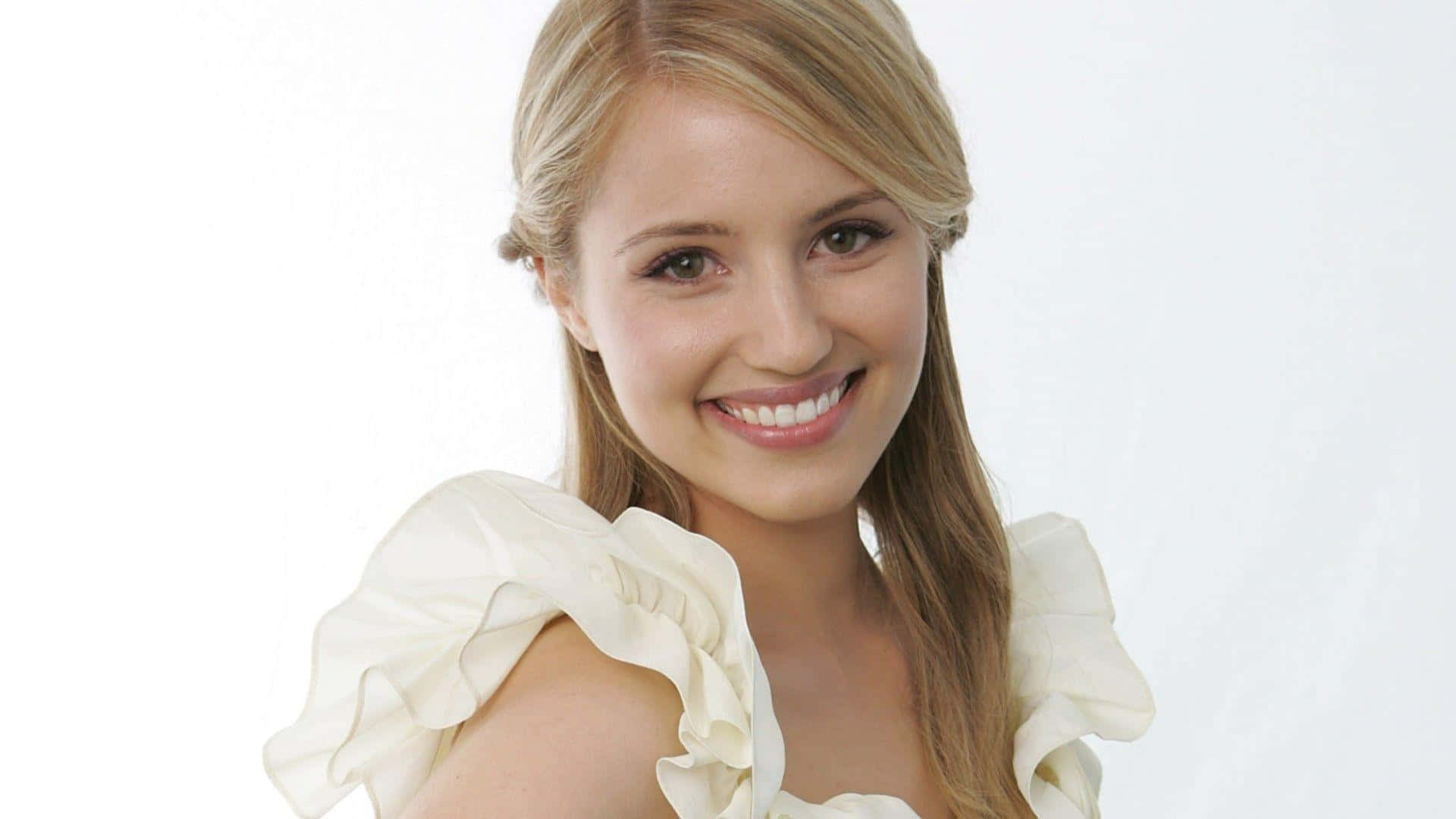 dianna agron 桌布 壁紙 — 一位開朗的金髮女性面帶燦爛笑容，身穿奶油色荷葉邊上衣，背景為純白色。