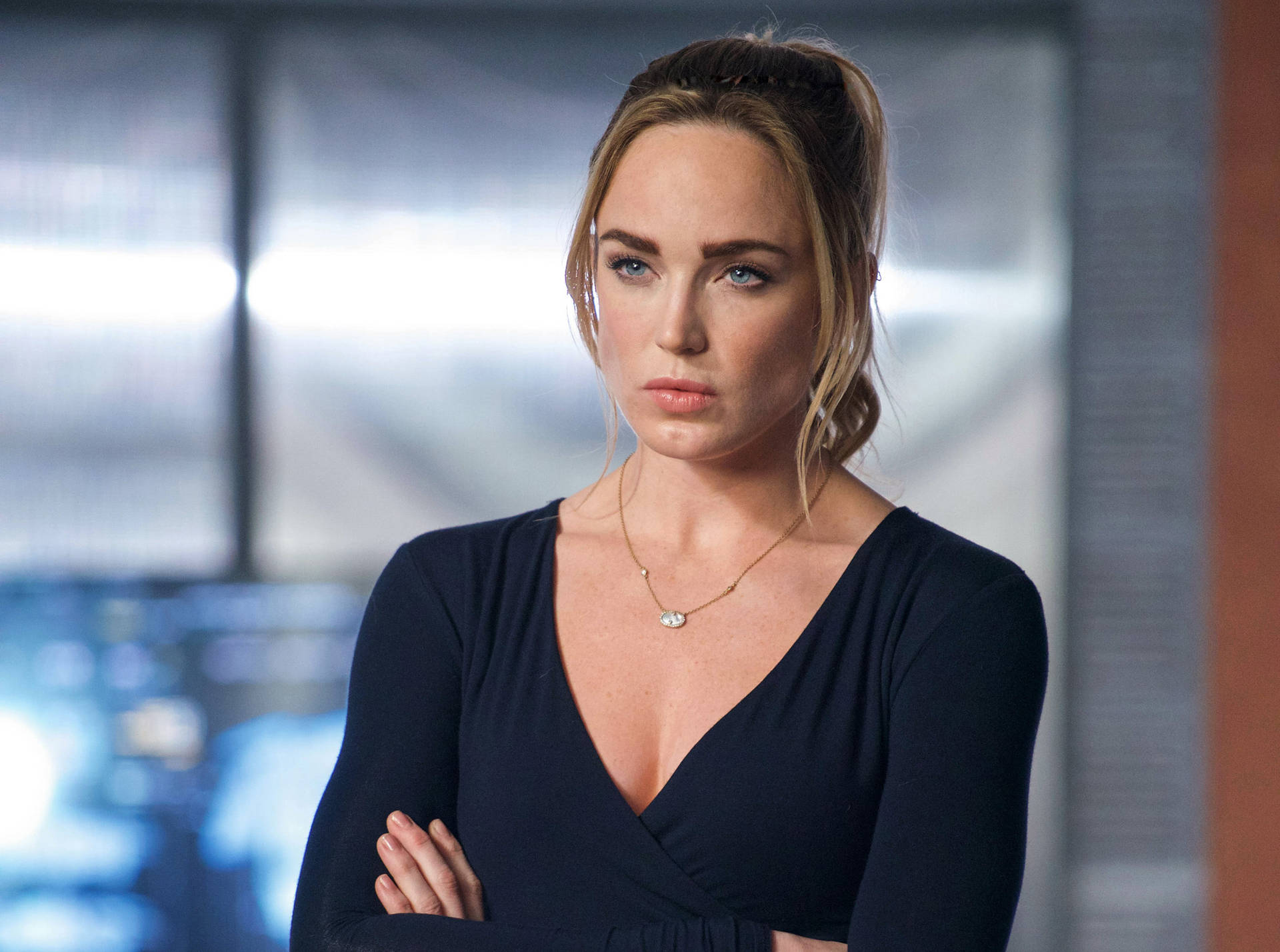 穿著黑色連衣裙的嚴肅女性在辦公室中雙臂交叉站立。 — Caity Lotz 動圖 壁紙