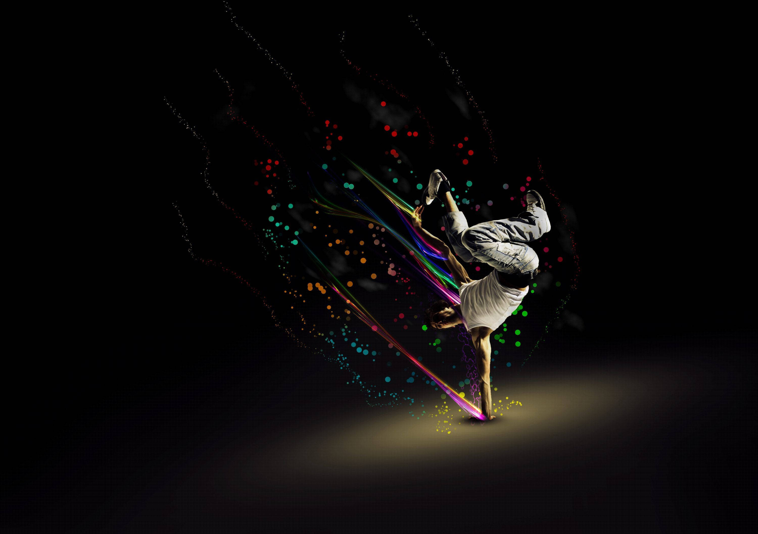 dancer 桌布 壁紙 — 一位霹靂舞者在黑色背景上表演動態倒立旋轉，伴隨著鮮豔多彩的光跡和粒子效果。