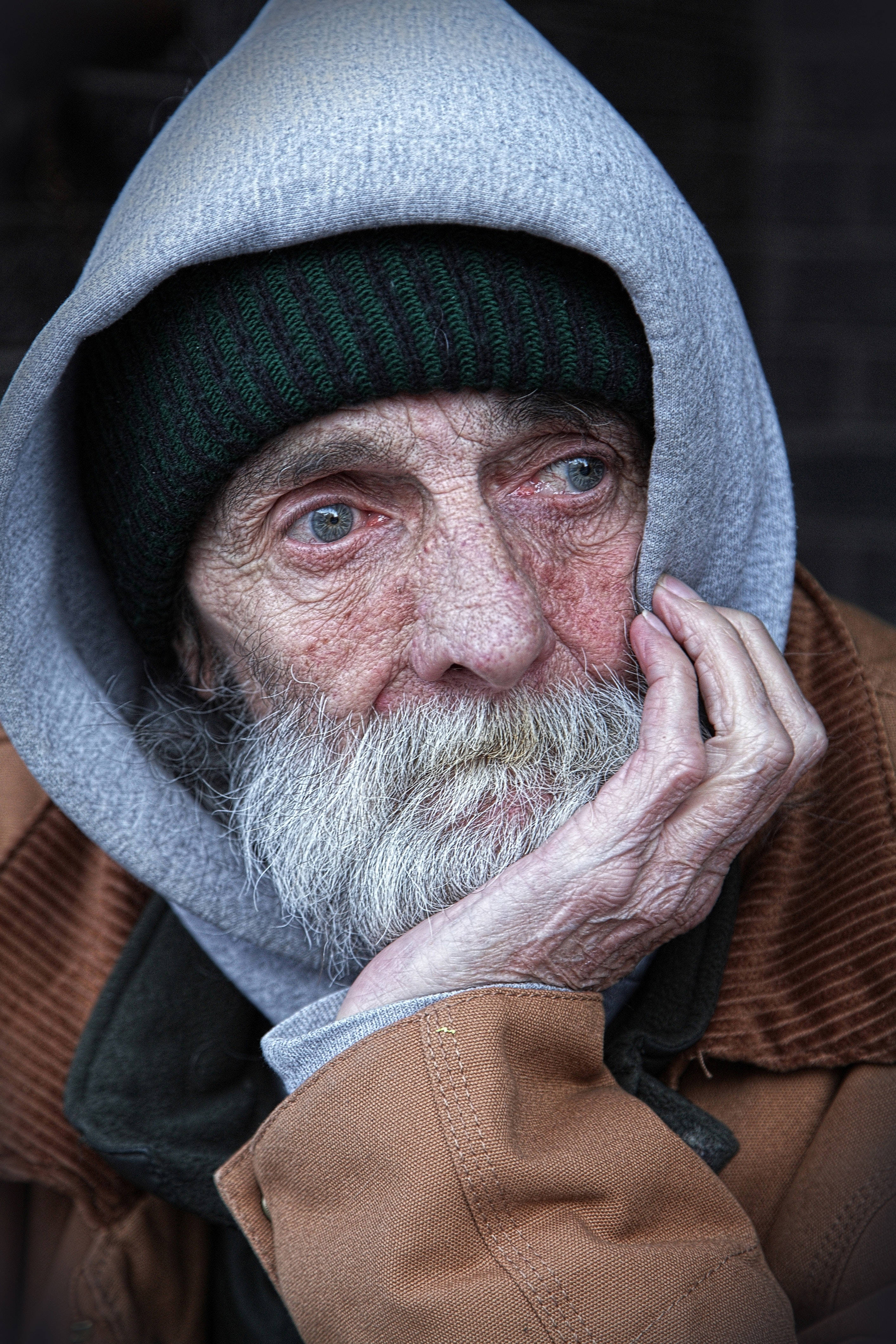 人像動態 桌布 壁紙 — 一位面容滄桑、留著白鬍子的老人穿著連帽外套和毛帽的特寫肖像。