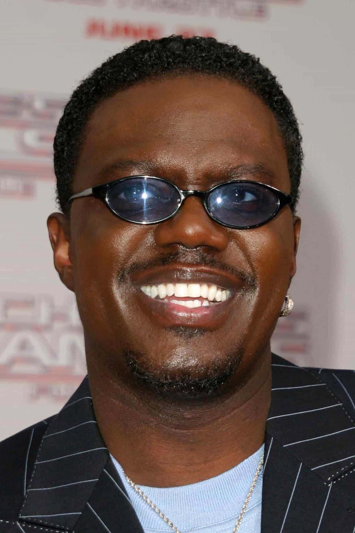 Celebrity 桌布 壁紙 — 一位面帶微笑、戴著深色太陽眼鏡和細條紋西裝的男士在紅地毯活動中自信地擺姿勢。