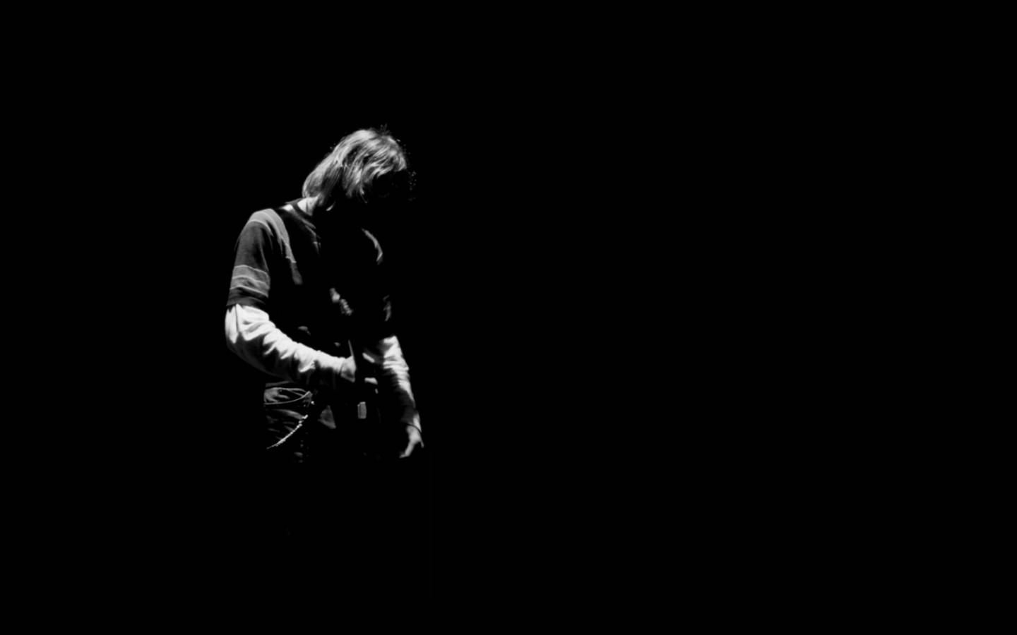 Rock 桌布 壁紙 — 一位音樂家在剪影中彈吉他，單一聚光燈打在漆黑背景上。