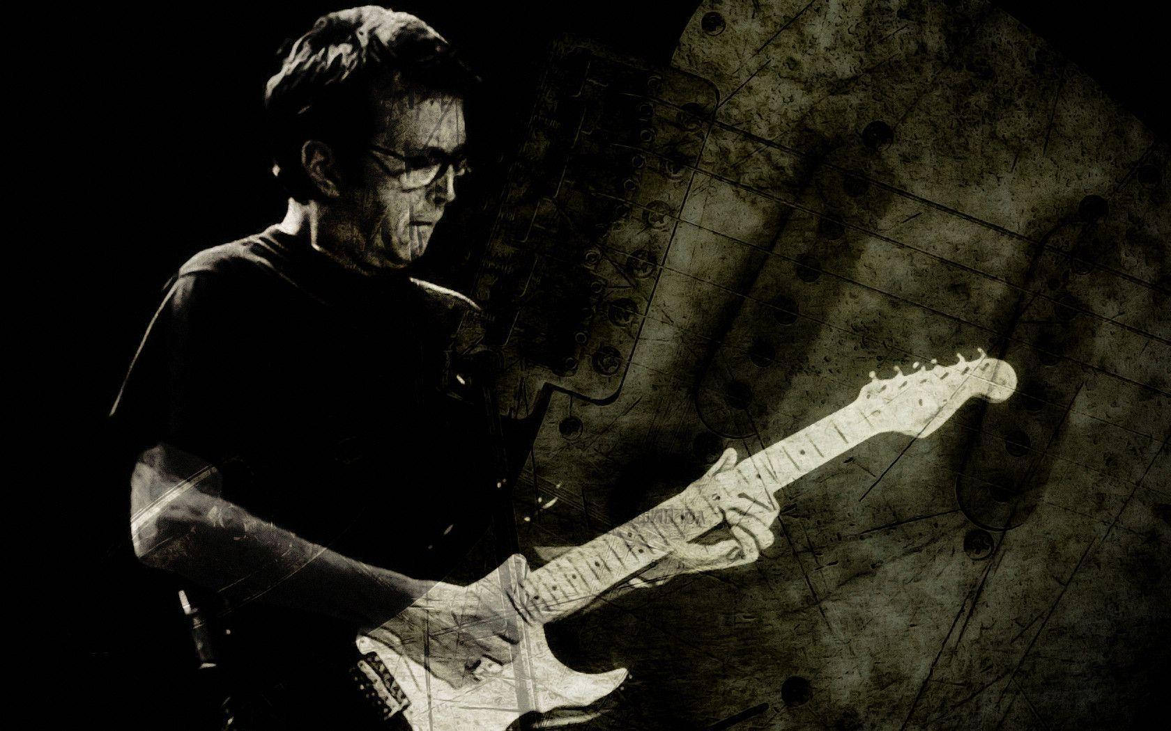 guitar player 桌布 壁紙 — 一位音樂家在戲劇性的舞台燈光下彈奏電吉他，背景帶有粗糙的紋理。