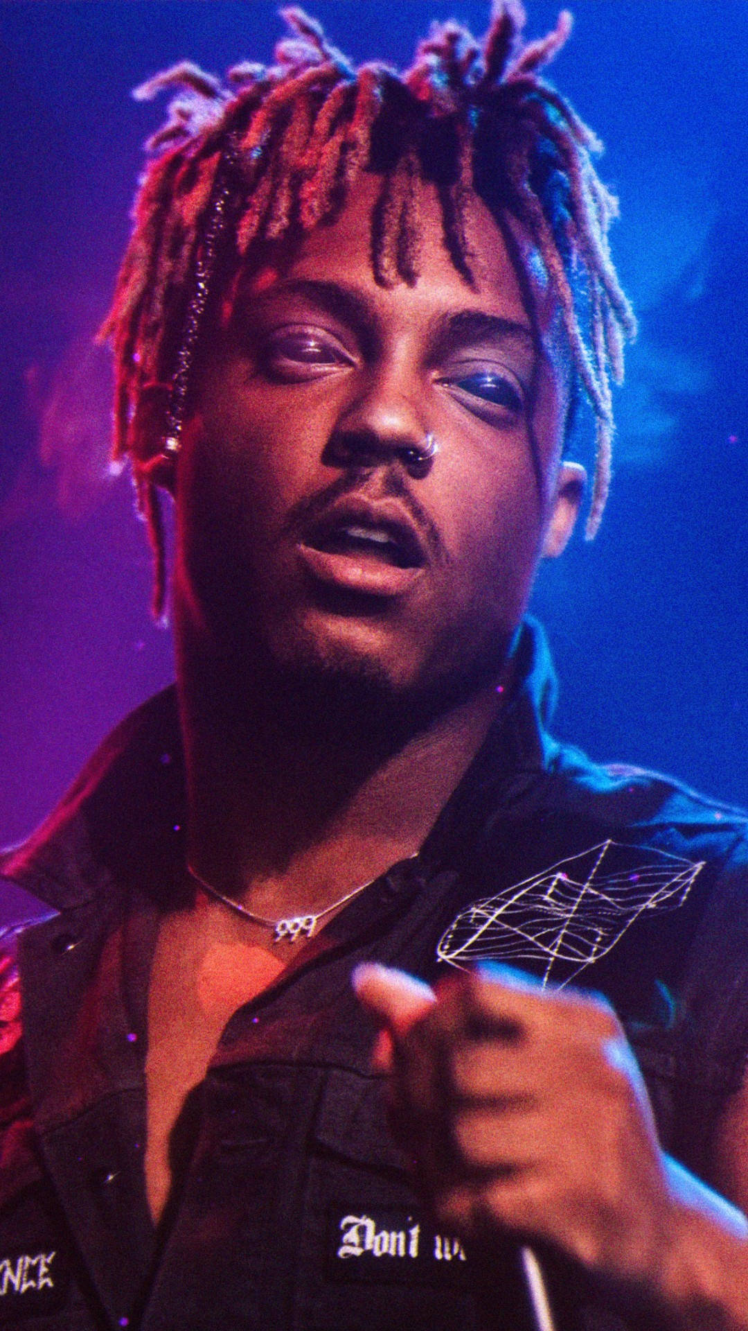 音樂家留著紅色和藍色辮子，在舞台燈光下向前指。 — Juice Wrld 壁紙