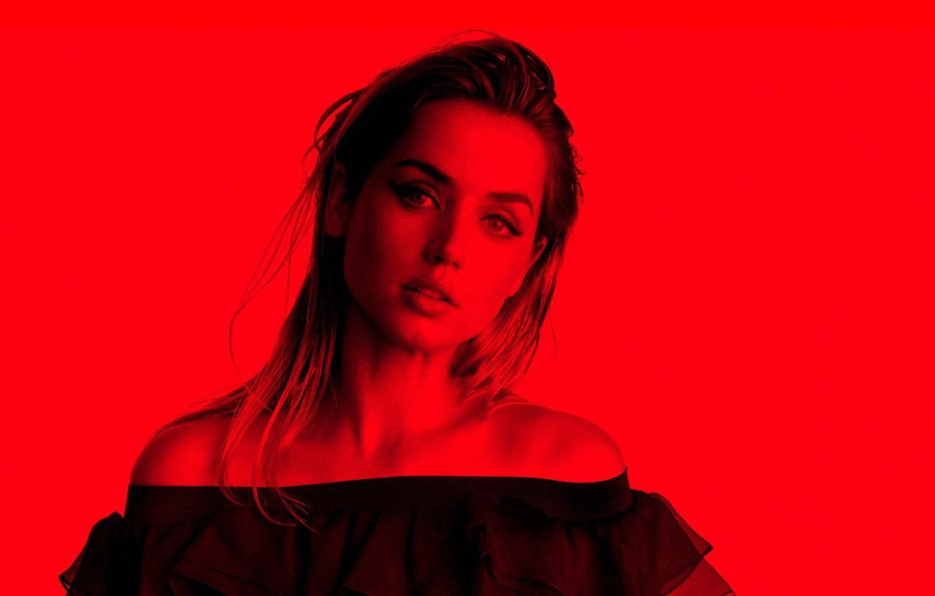 ana de armas 桌布 壁紙 — 一位頭髮凌亂的女性，在飽和的紅色背景前，穿著黑色露肩上衣，眼神強烈地凝視。