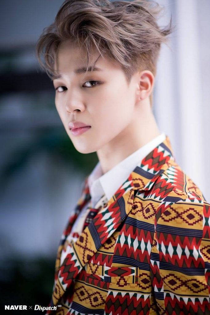 BTS 智旻 桌布 壁紙 — 一位頭髮凌亂的年輕男子穿著鮮豔的幾何圖案西裝外套，背景柔和模糊。