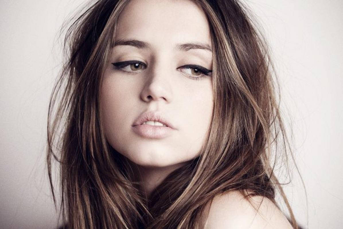 ana de armas 桌布 壁紙 — 一位頭髮凌亂的棕色頭髮、煙燻眼妝的女性特寫肖像，在中性背景前柔和地凝視。