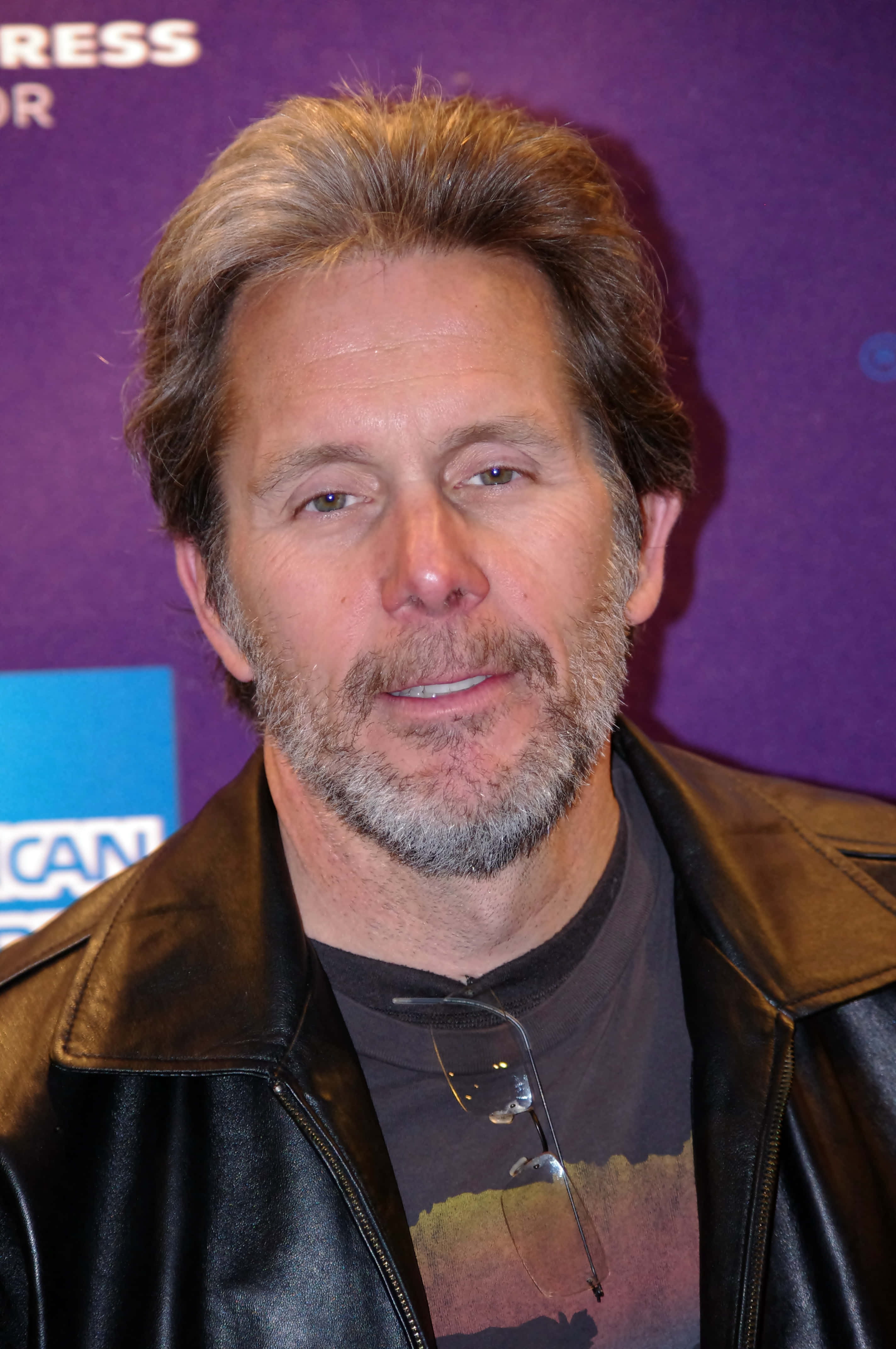 Gary Cole 桌布 壁紙 — 一位頭髮花白、留鬍子的男士穿著皮夾克，眼鏡掛在衣領上，背景為紫色。