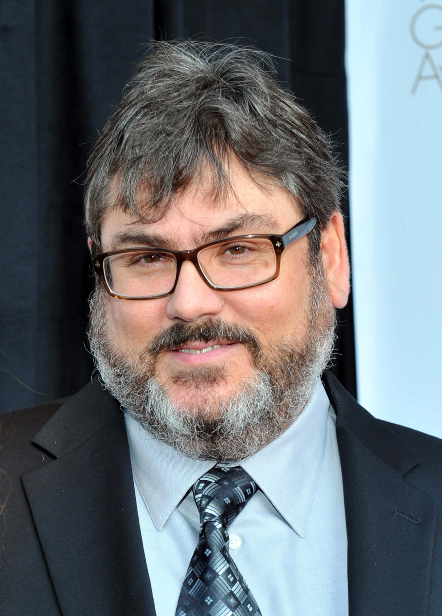Paul Dini 桌布 壁紙 — 一位頭髮花白、留鬍鬚的男士的近距離肖像，戴著眼鏡、西裝和圖案領帶，對著鏡頭微笑。