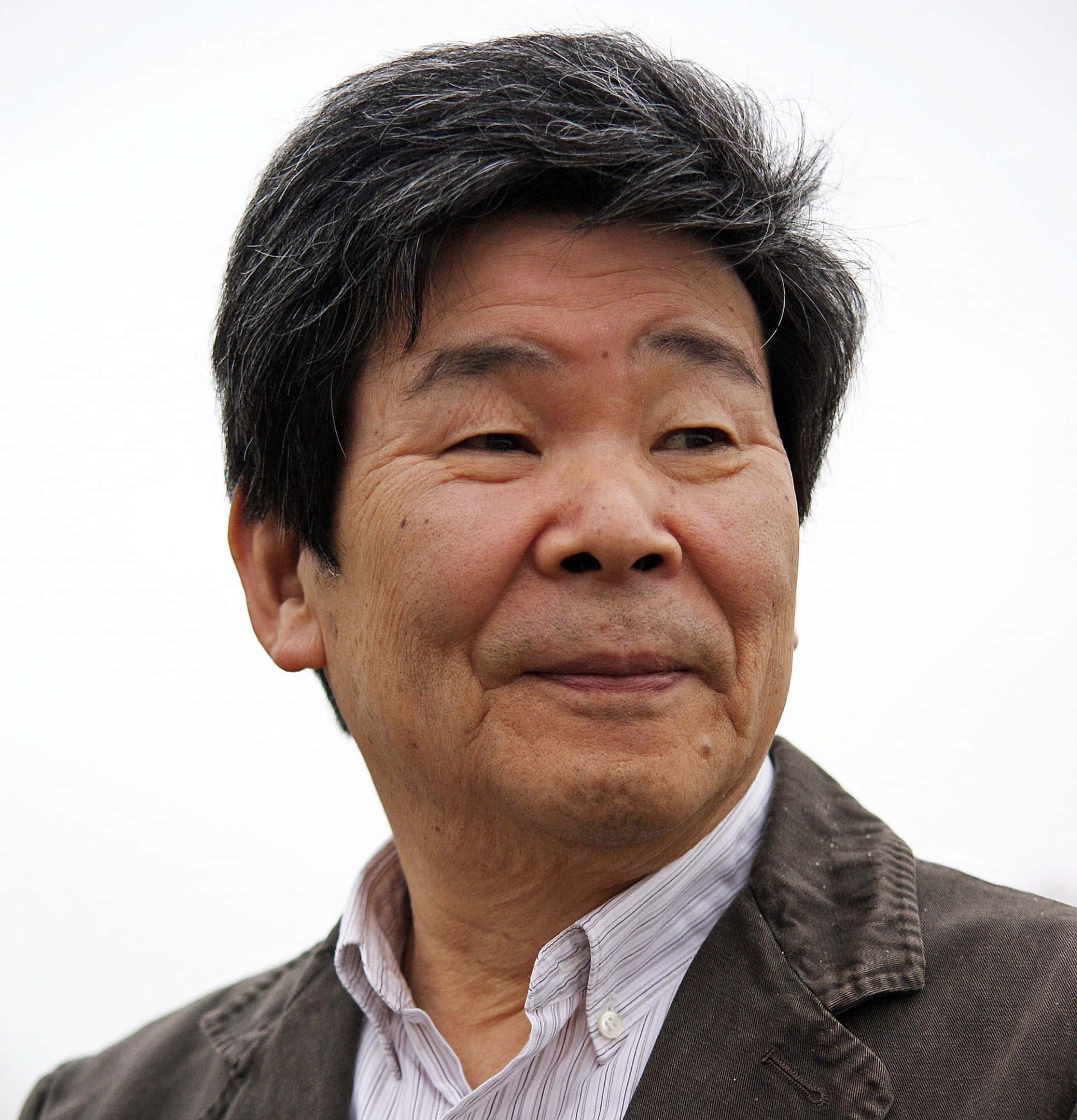 Isao Takahata 桌布 壁紙 — 一位頭髮花白的年長亞洲男子在純白背景前溫柔微笑的特寫肖像。