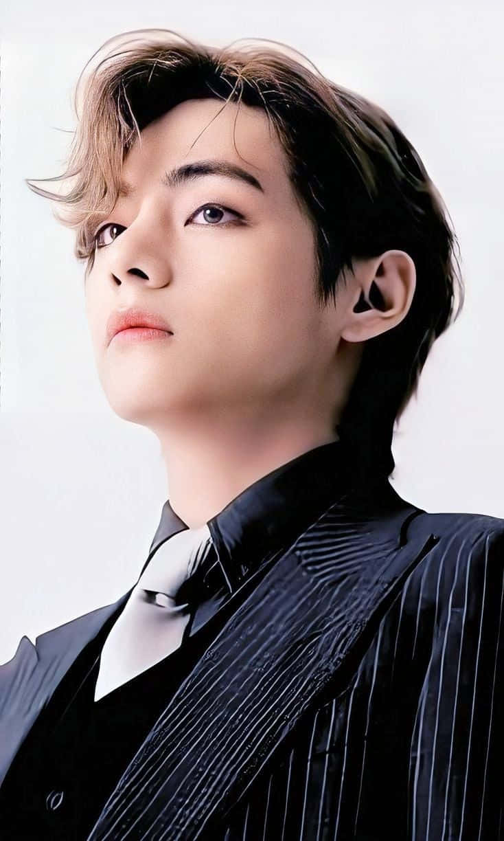 BTS V 動圖 桌布 壁紙 — 一位頭髮蓬鬆的年輕男子穿著時尚的黑色細條紋西裝，在純白背景前向上凝視。