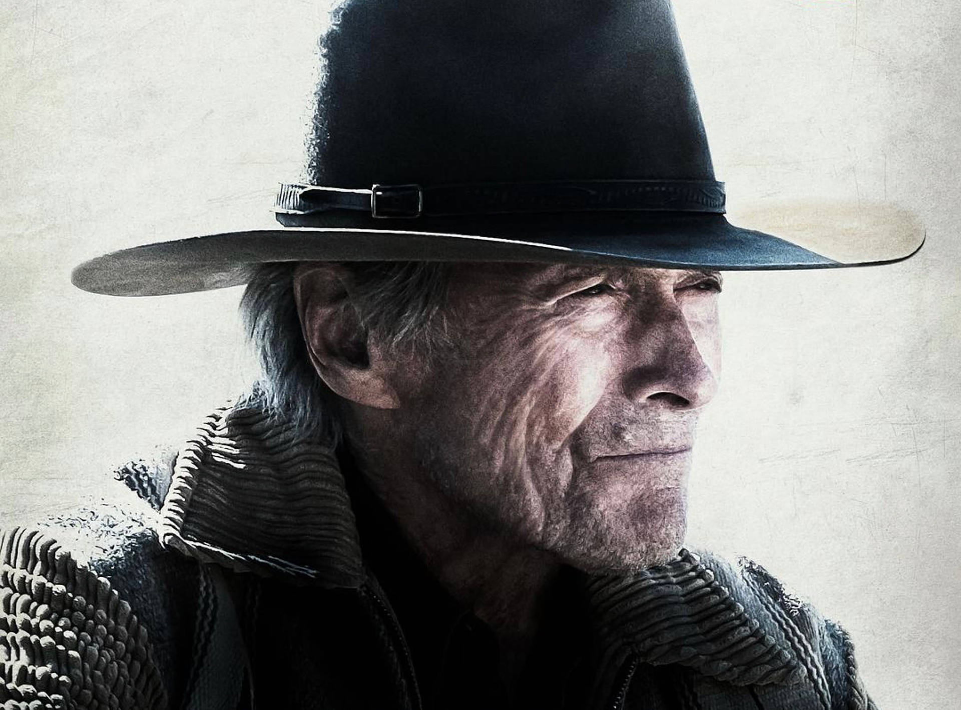 Cowboy 桌布 壁紙 — 一位飽經風霜的牛仔戴著黑色帽子，在帶有紋理的米白色背景前若有所思地凝視。