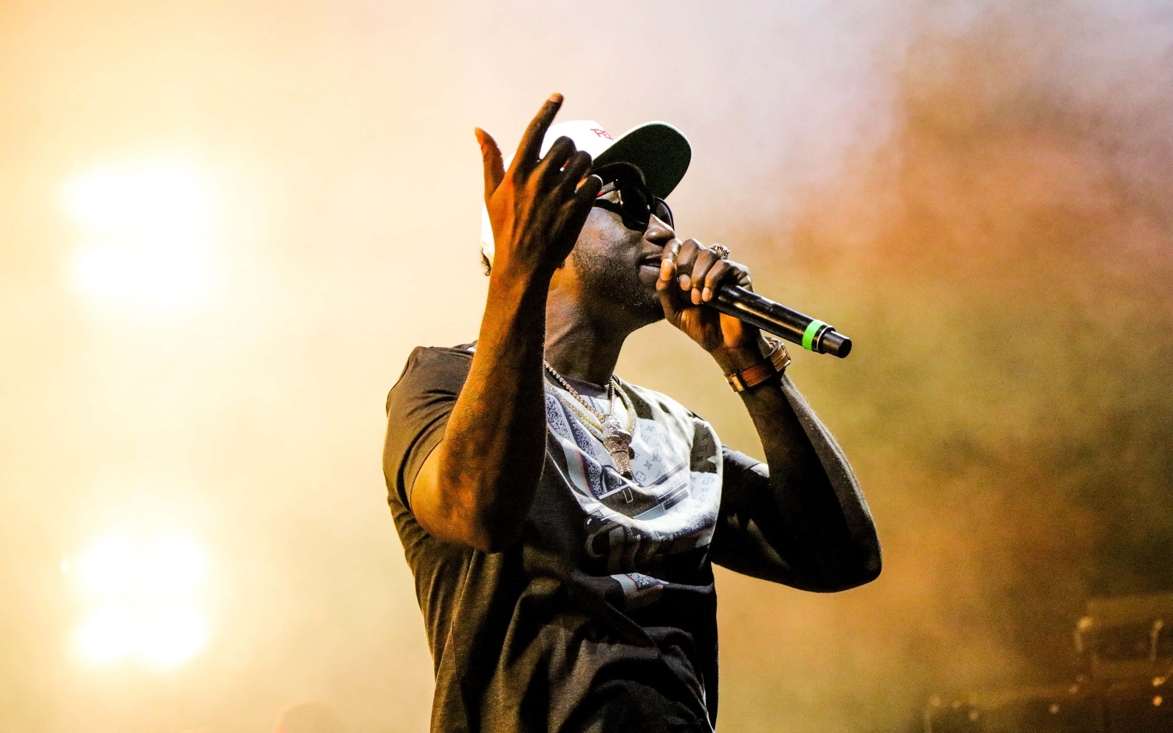 4K Rapper 桌布 壁紙 — 一位饒舌歌手在明亮燈光下，煙霧繚繞中，於舞台上熱情表演。