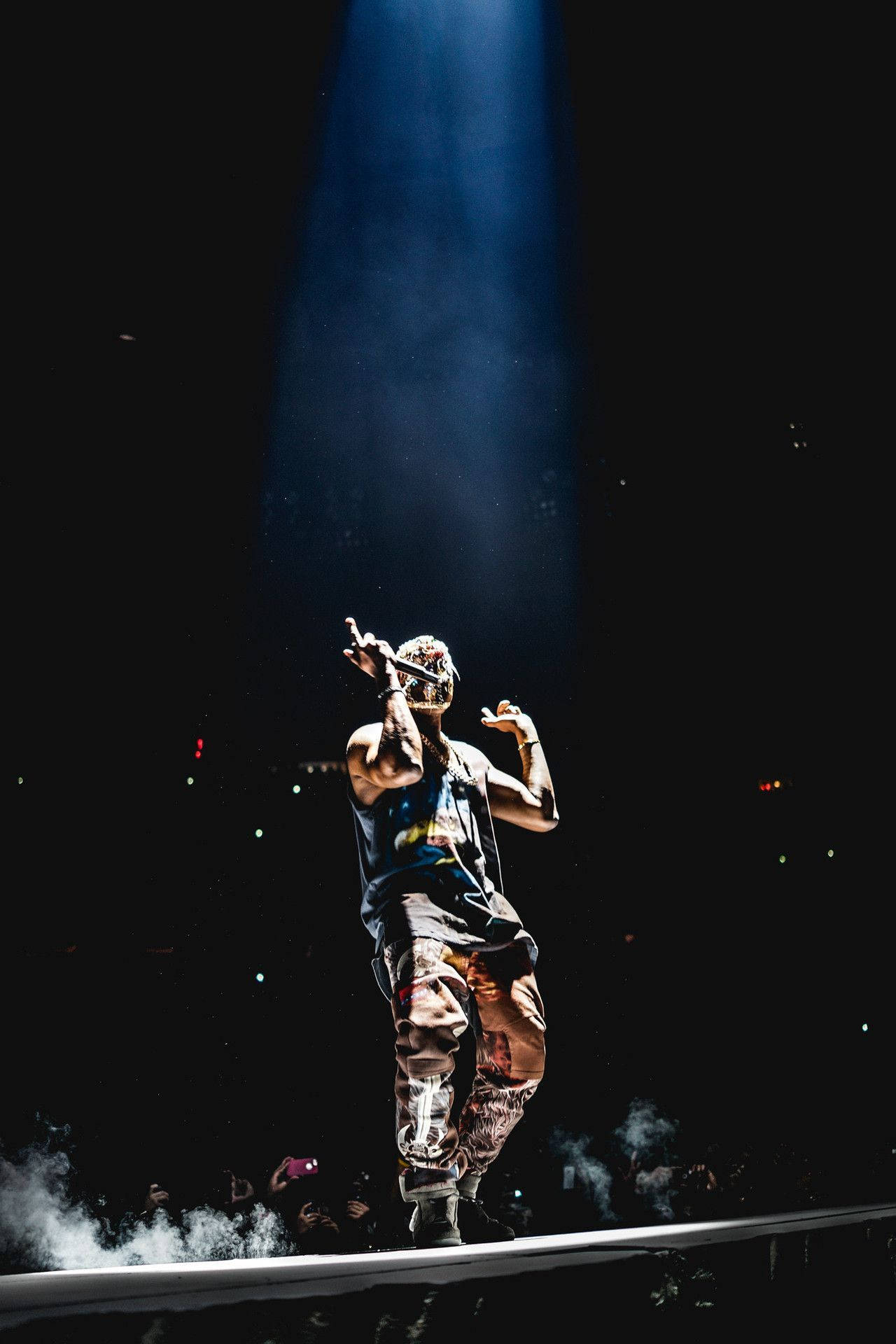 Kanye 桌布 壁紙 — 一位饒舌歌手在煙霧瀰漫的舞台上，僅靠一盞聚光燈，面對熱情的觀眾表演。