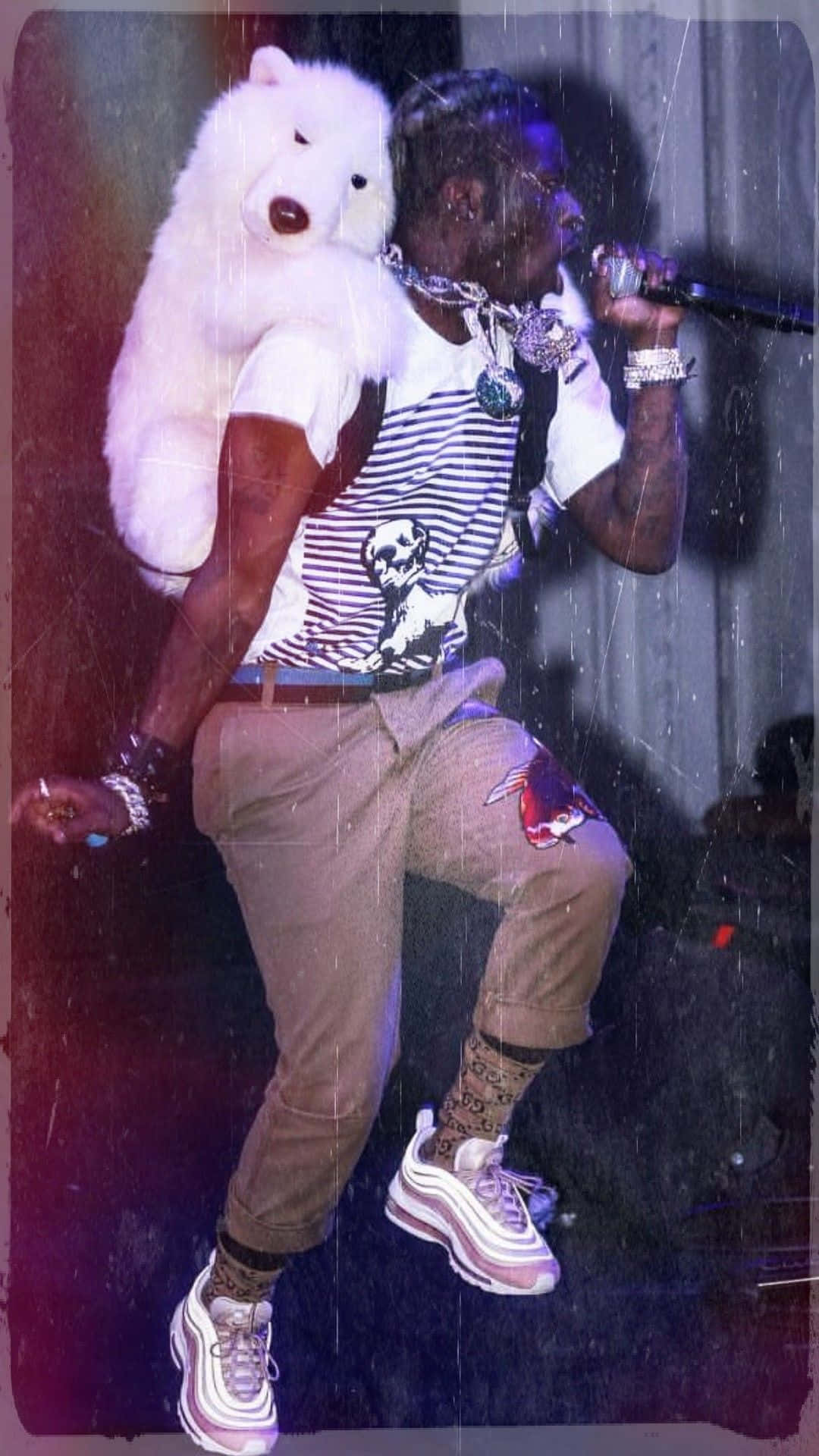 Rappers 桌布 壁紙 — 一位饒舌歌手在舞台上表演，肩上扛著一個大型白色北極熊毛絨玩具，在充滿活力的舞台燈光下。