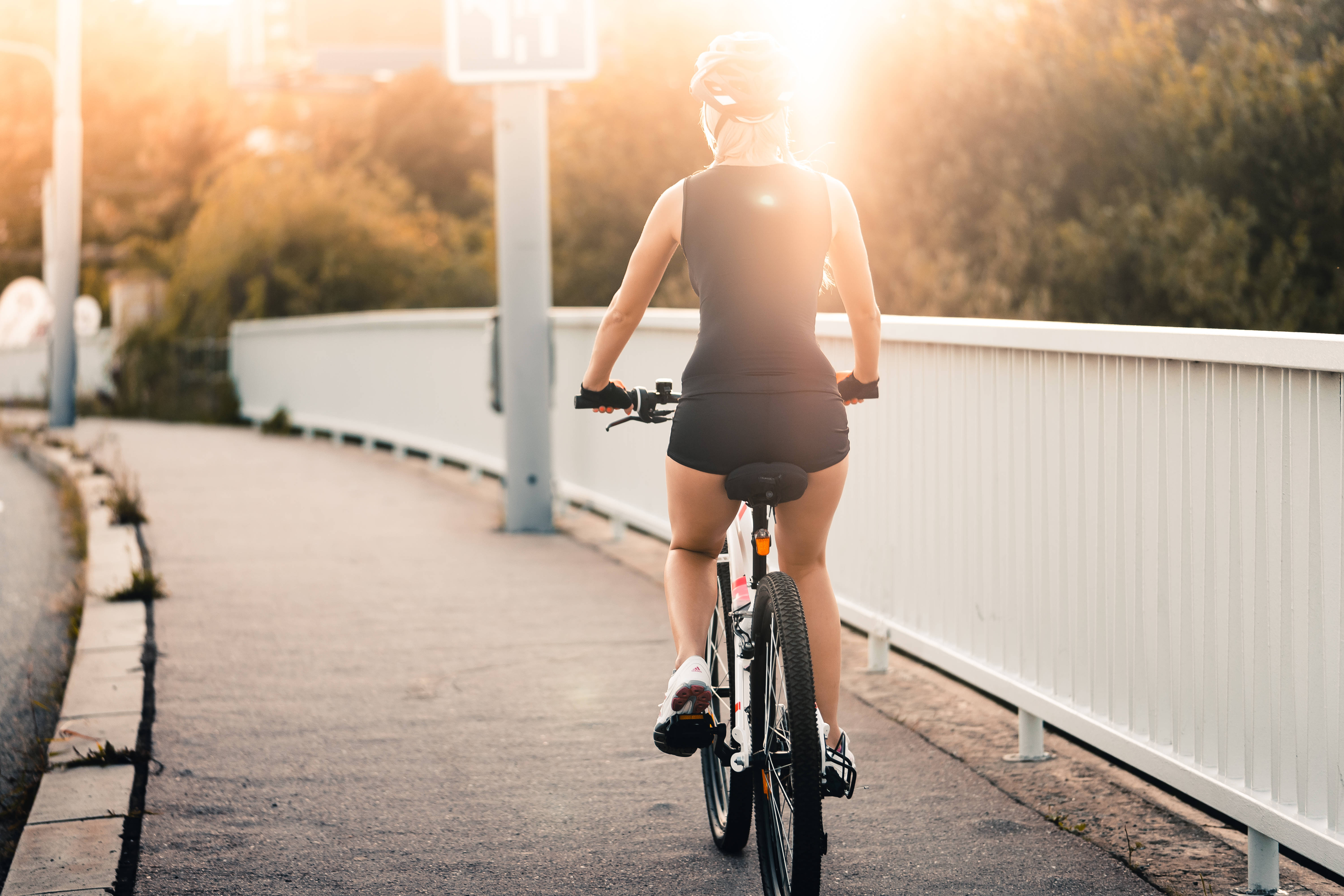 4K bike 桌布 壁紙 — 一位騎自行車的人在黃金時段騎著自行車過橋，背後有太陽眩光。