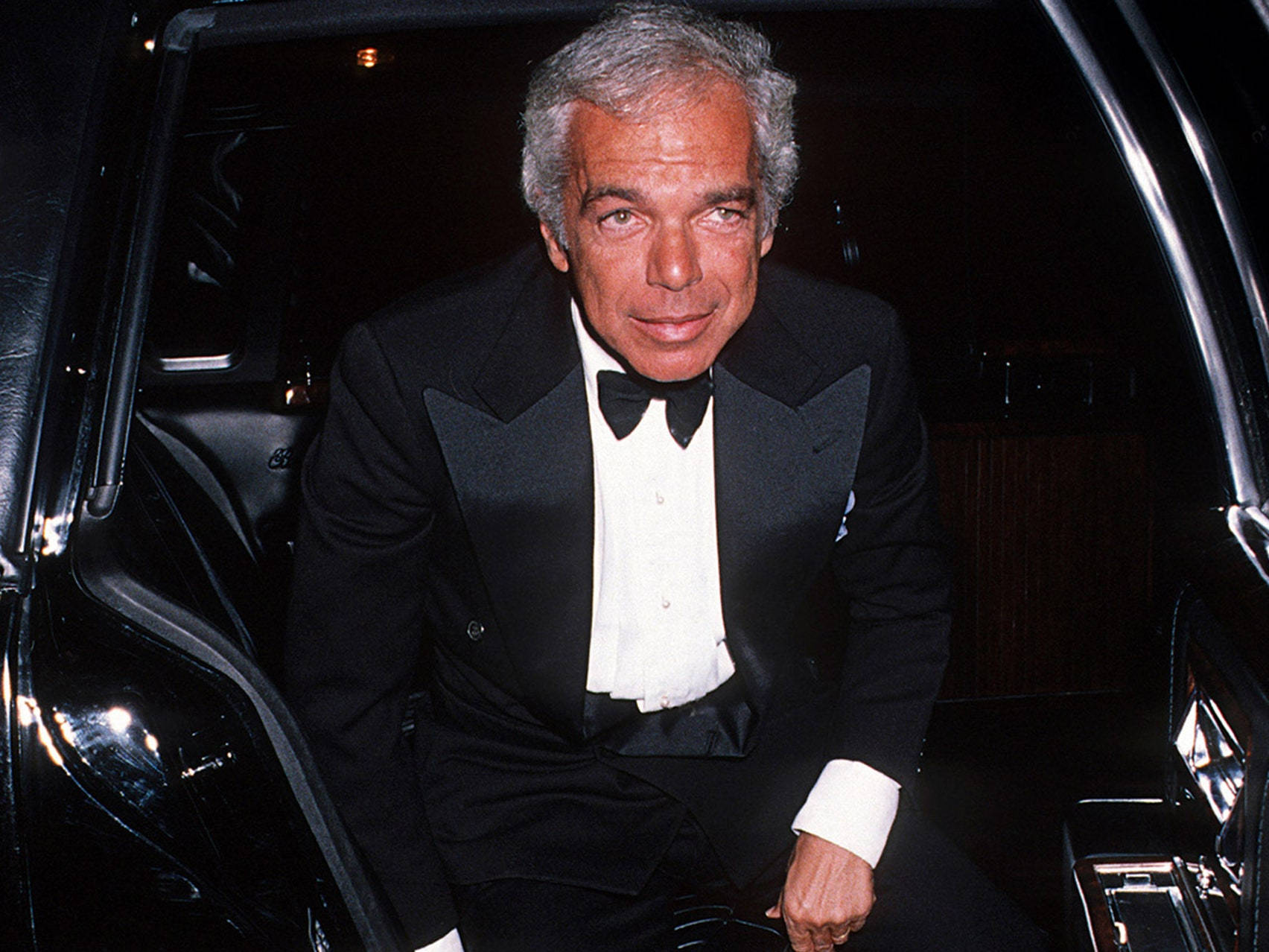ralph lauren 桌布 壁紙 — 一位高貴男士身穿黑色燕尾服配領結，夜晚從豪華車中步出。