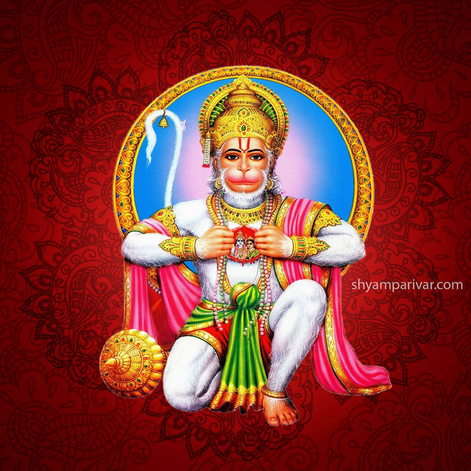 hanuman ji HD 桌布 壁紙 — 一位高貴的猴神穿著金色和粉紅色的長袍，盤腿而坐，手持神聖圖標，背景是豐富的紅色佩斯利花紋。