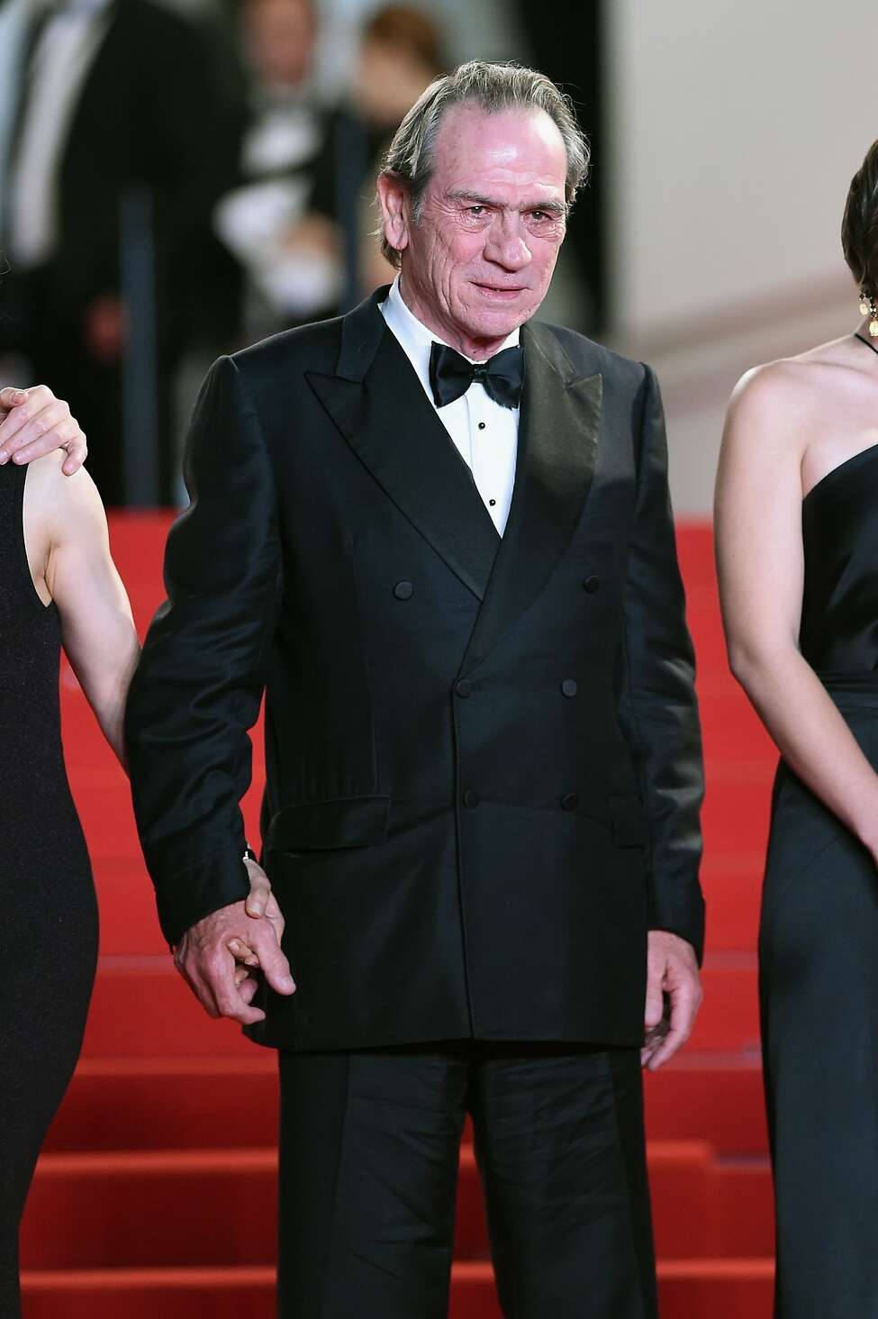 Celebrity 桌布 壁紙 — 一位高貴的老年男士身穿黑色燕尾服，在兩位身穿優雅黑色長裙的女性陪同下走過紅地毯。