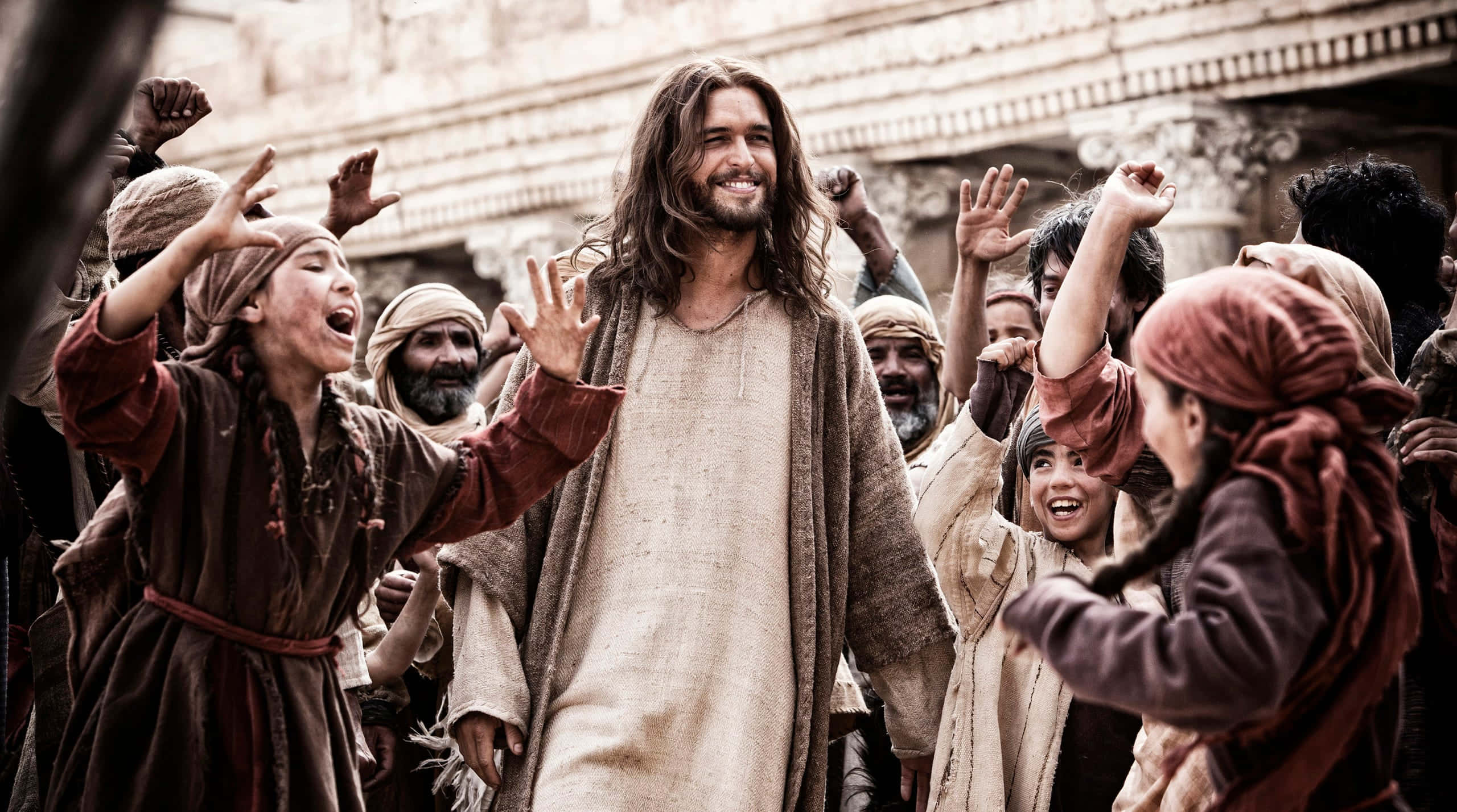 Son Of God 桌布 壁紙 — 一位鬍鬚男身穿米色長袍，穿過一群歡樂舉手慶祝的人群。