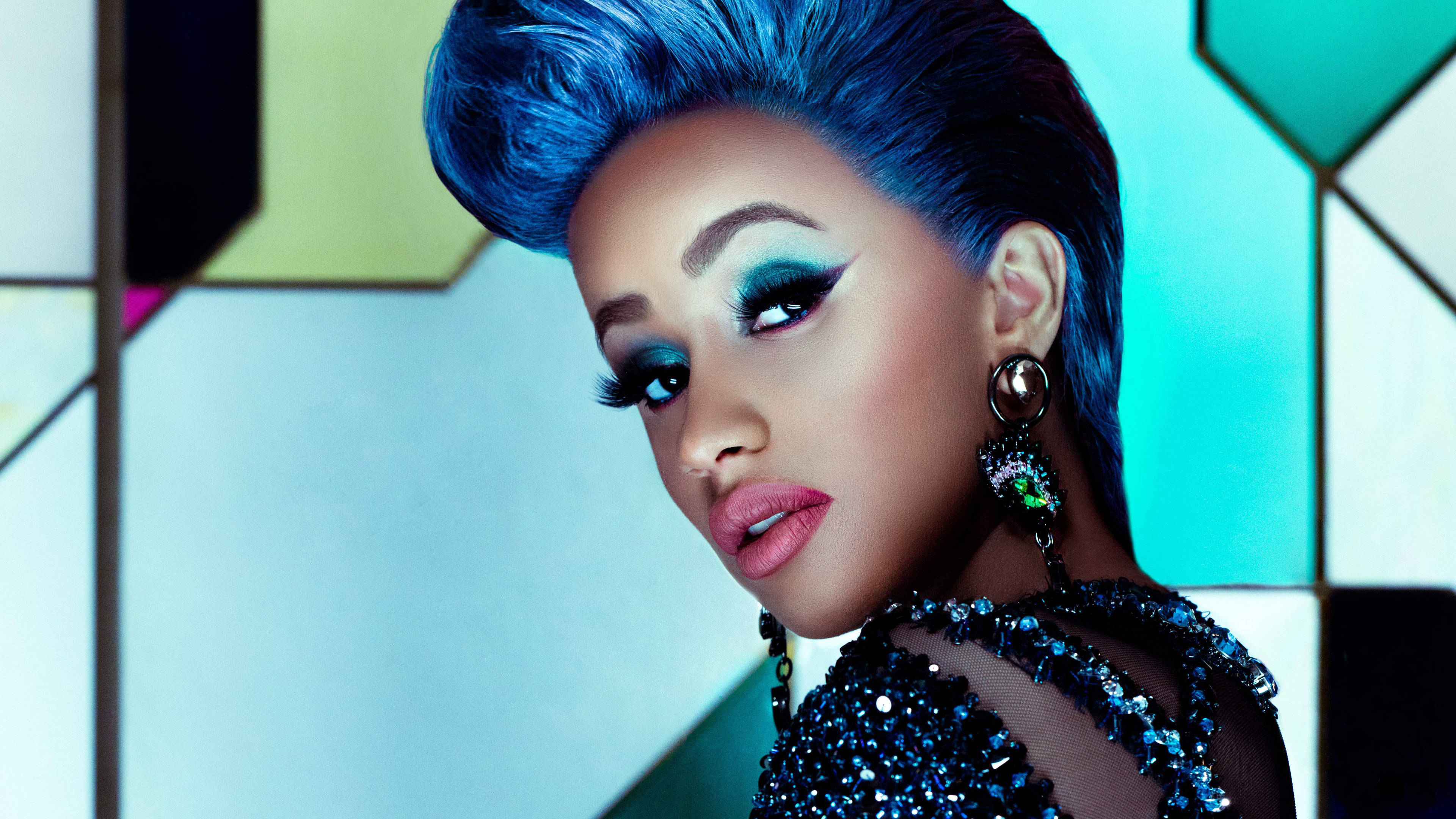 cardi 桌布 壁紙 — 一位魅力四射的女性，擁有電光藍色頭髮和大膽妝容，在幾何彩色玻璃背景前擺姿勢。