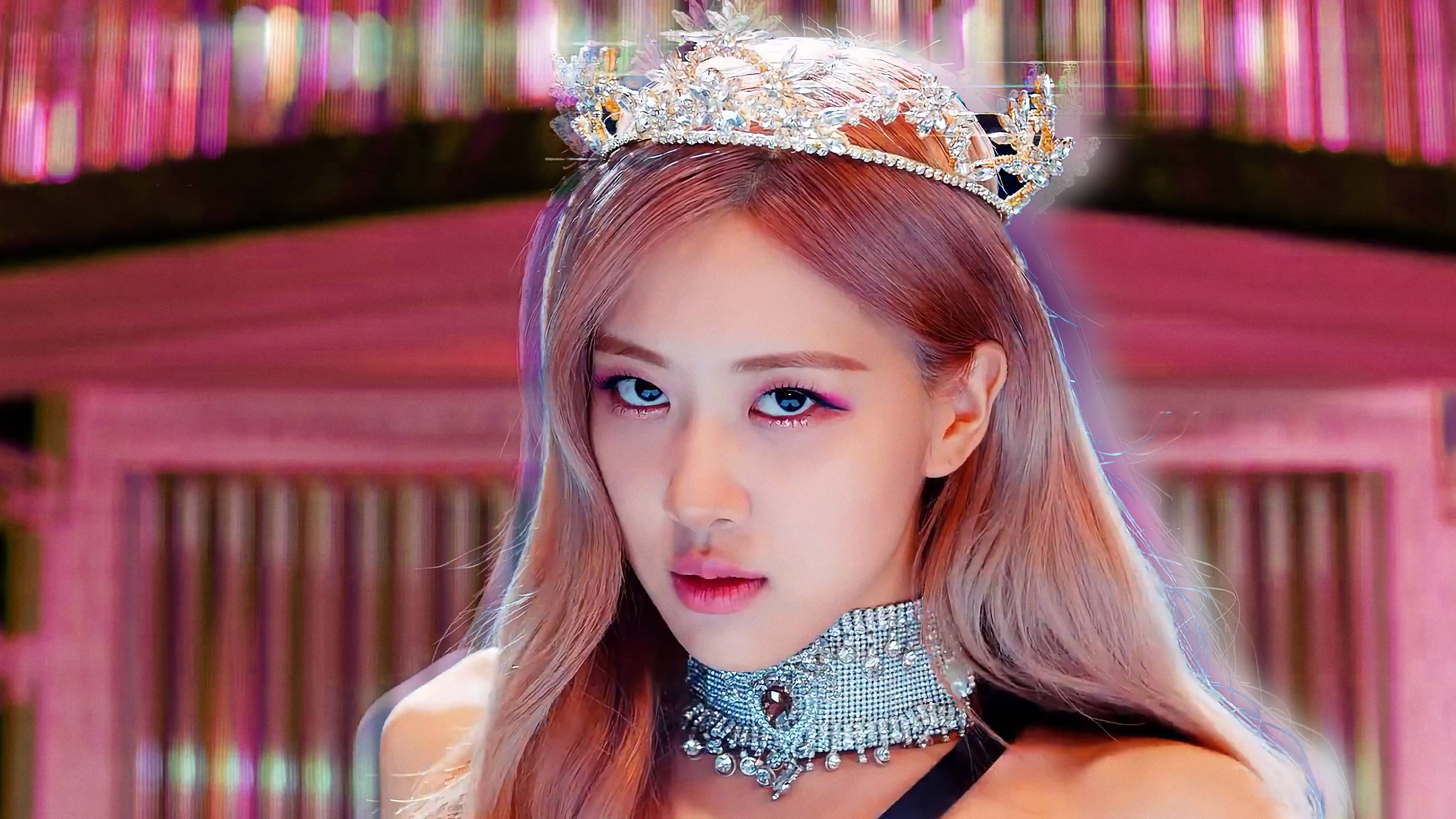 Rose Blackpink 桌布 壁紙 — 一位魅力四射的粉紅髮女性，戴著鑲有寶石的王冠和頸鍊，背景是充滿活力的粉紅霓虹燈。